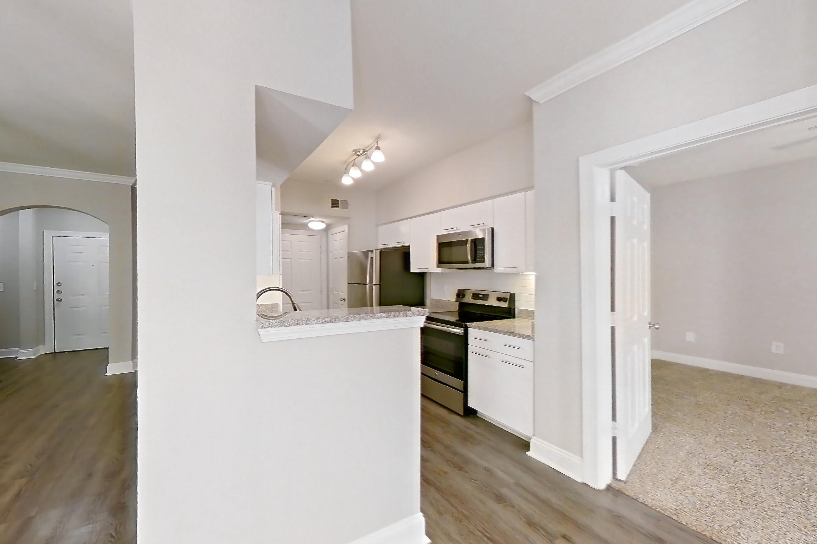 Dining room with dark wood-finish flooring, electric range, light stone countertops, microwave, oven/range, and stainless steel appliances, Apartment 6105 at Marq Perimeter