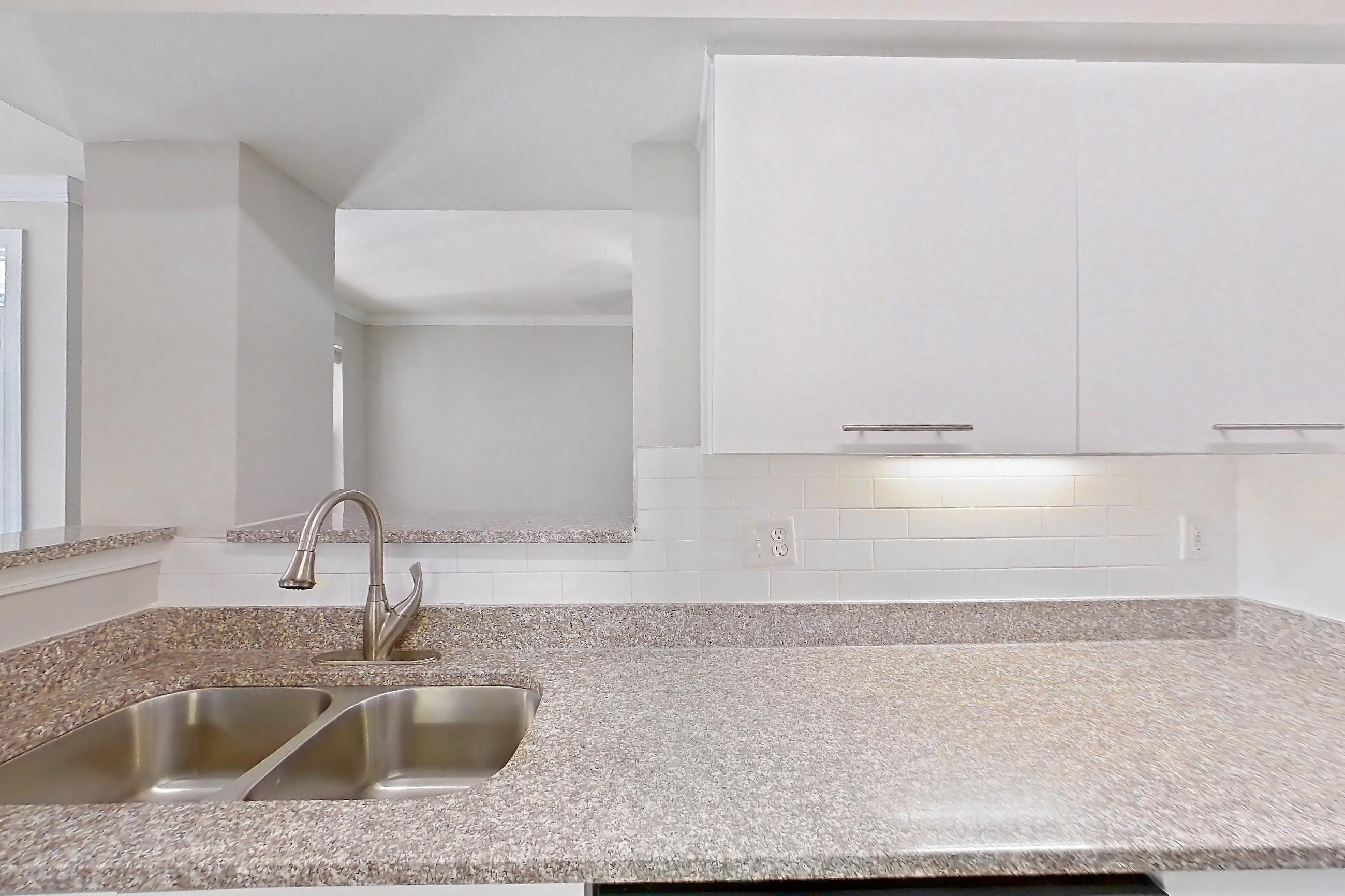 Kitchen with dark wood-finish flooring, dishwasher, electric range, light stone countertops, microwave, oven/range, refrigerator, and stainless steel appliances, Apartment 6105 at Marq Perimeter