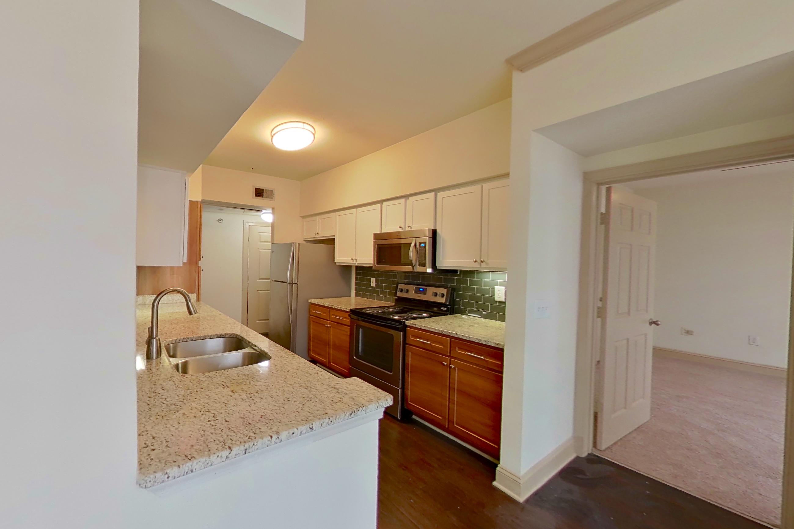 Dining area with dark wood-finish flooring, electric range, light countertops, light stone countertops, oven/range, stainless steel appliances, and wood-finish flooring, Apartment 6118 at Marq Perimeter