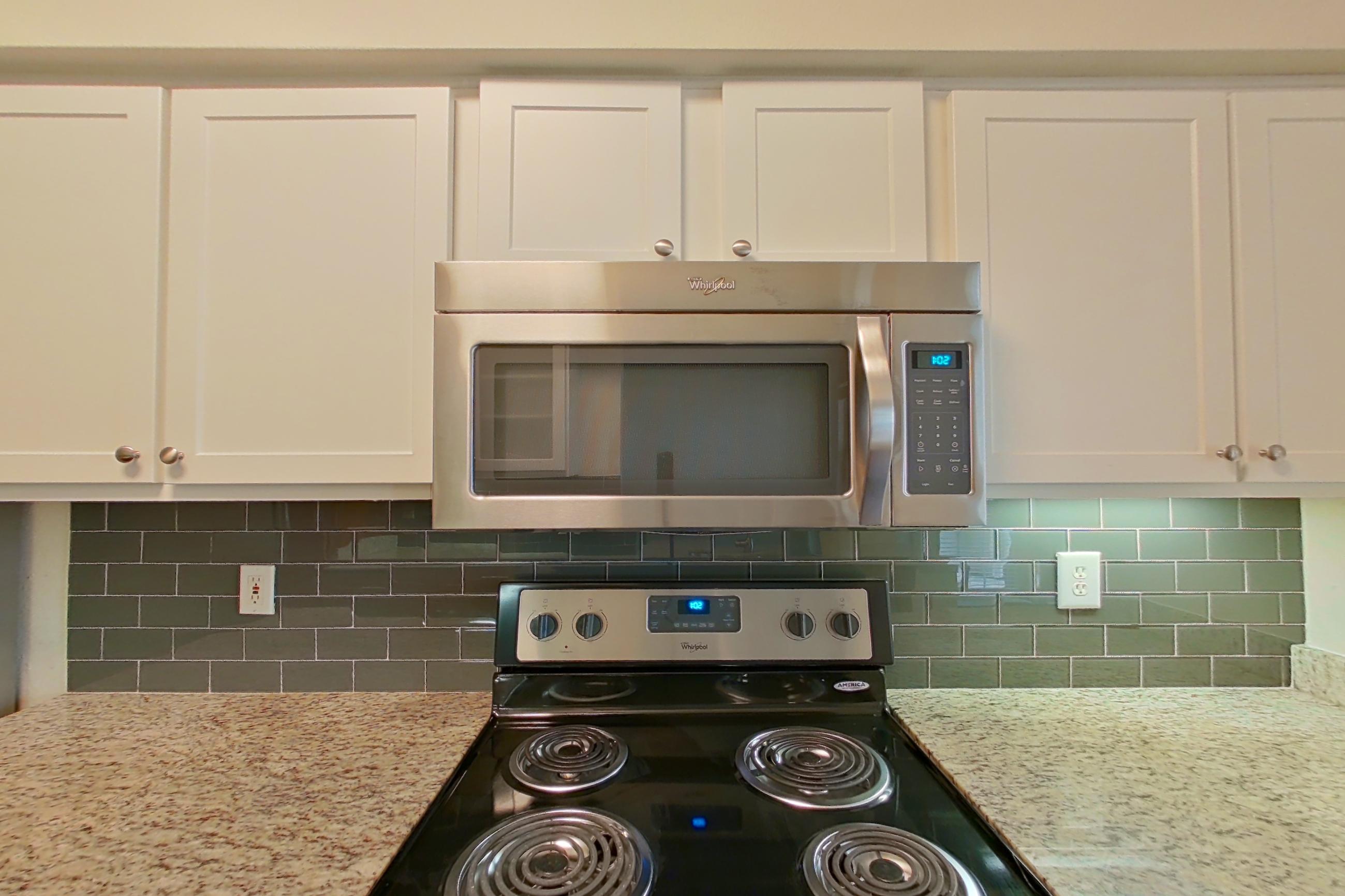 Kitchen with black appliances, dark wood-finish flooring, dishwasher, electric range, light stone countertops, oven/range, and stainless steel appliances, Apartment 6118 at Marq Perimeter