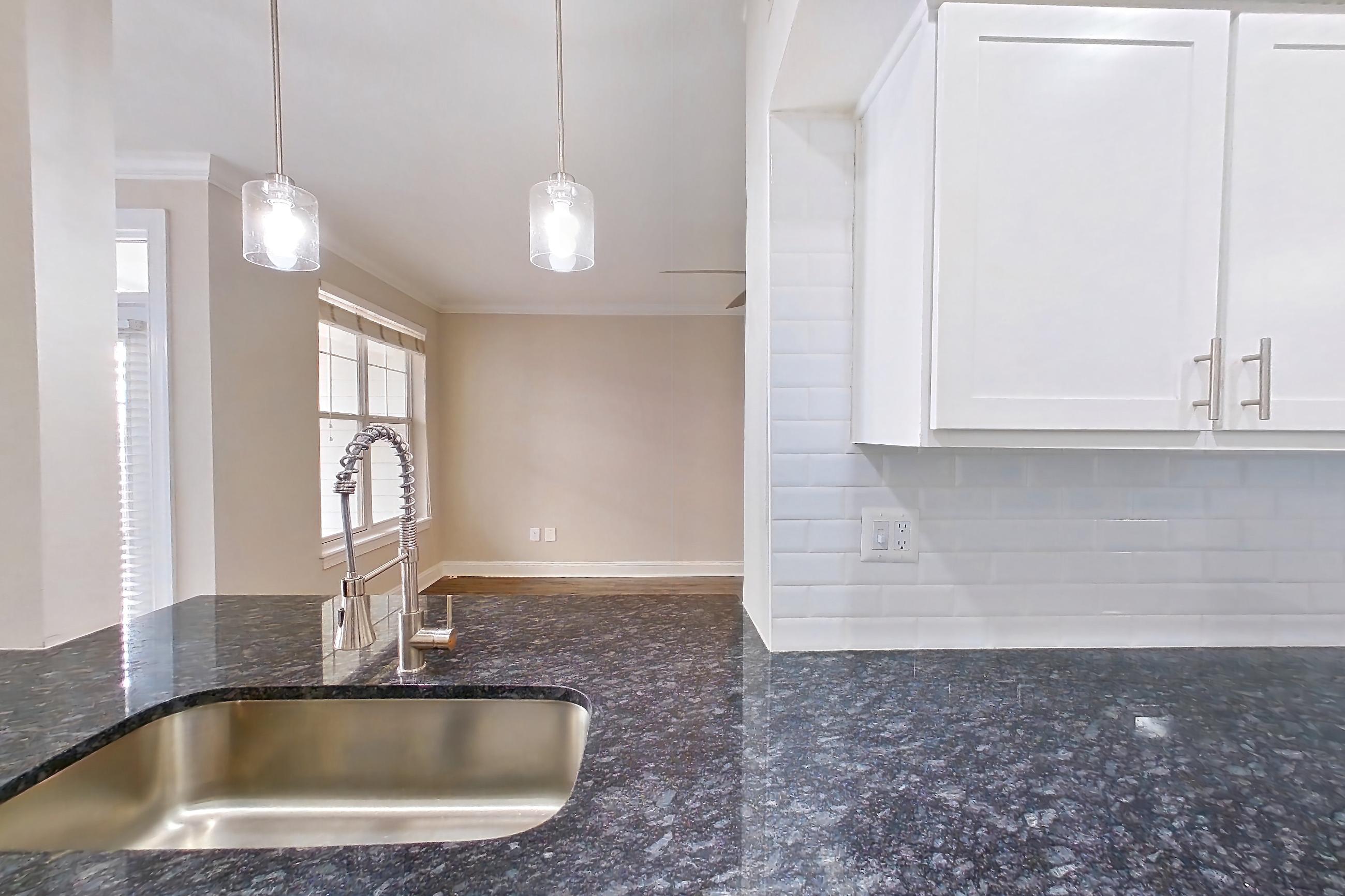 Kitchen with dark stone countertops, dishwasher, electric range, light countertops, light wood-finish flooring, microwave, oven/range, refrigerator, and stainless steel appliances, Apartment 6129 at Marq Perimeter