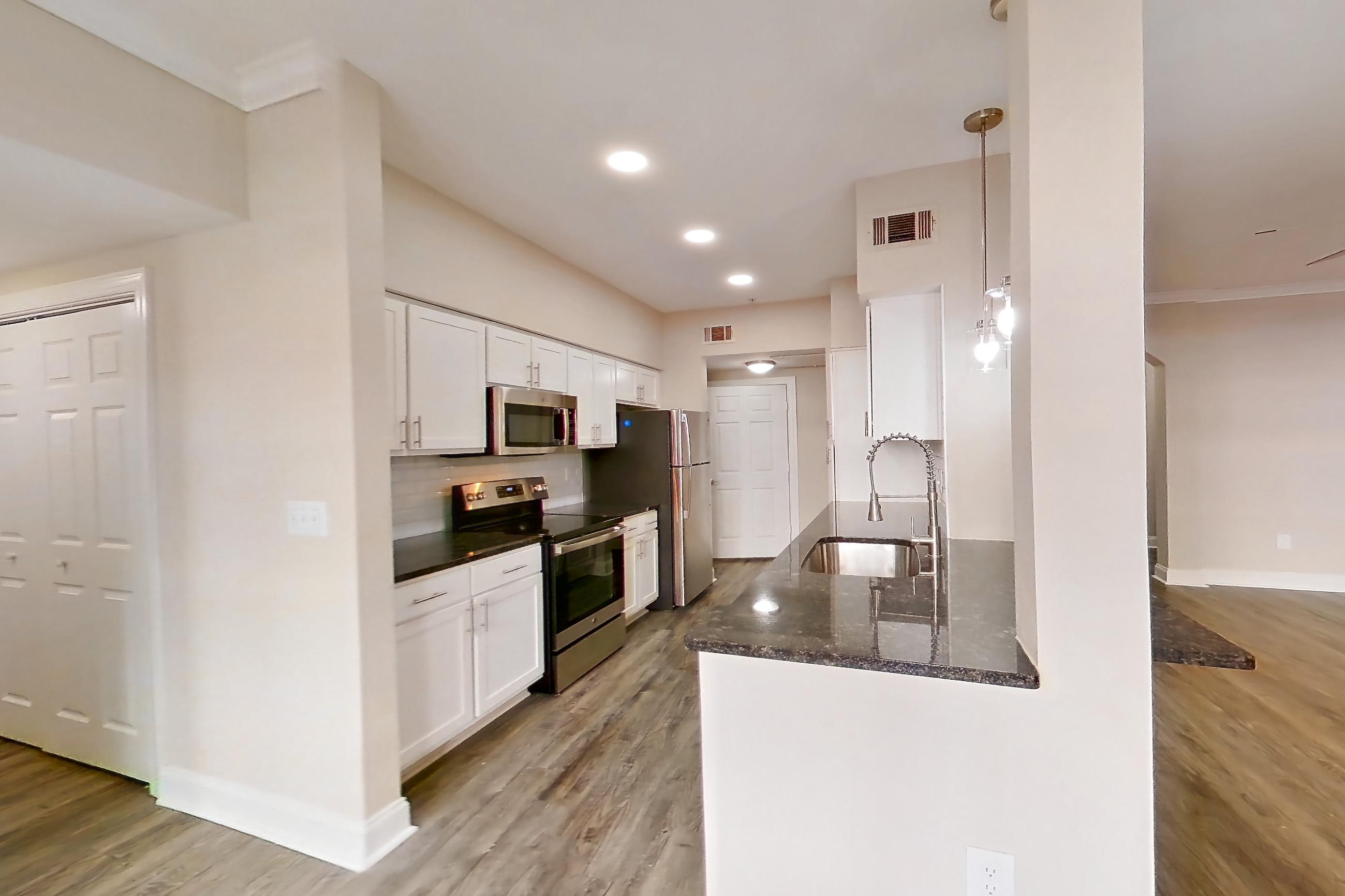 Dining room with dark stone countertops, electric range, light wood-finish flooring, microwave, oven/range, and stainless steel appliances, Apartment 6131 at Marq Perimeter