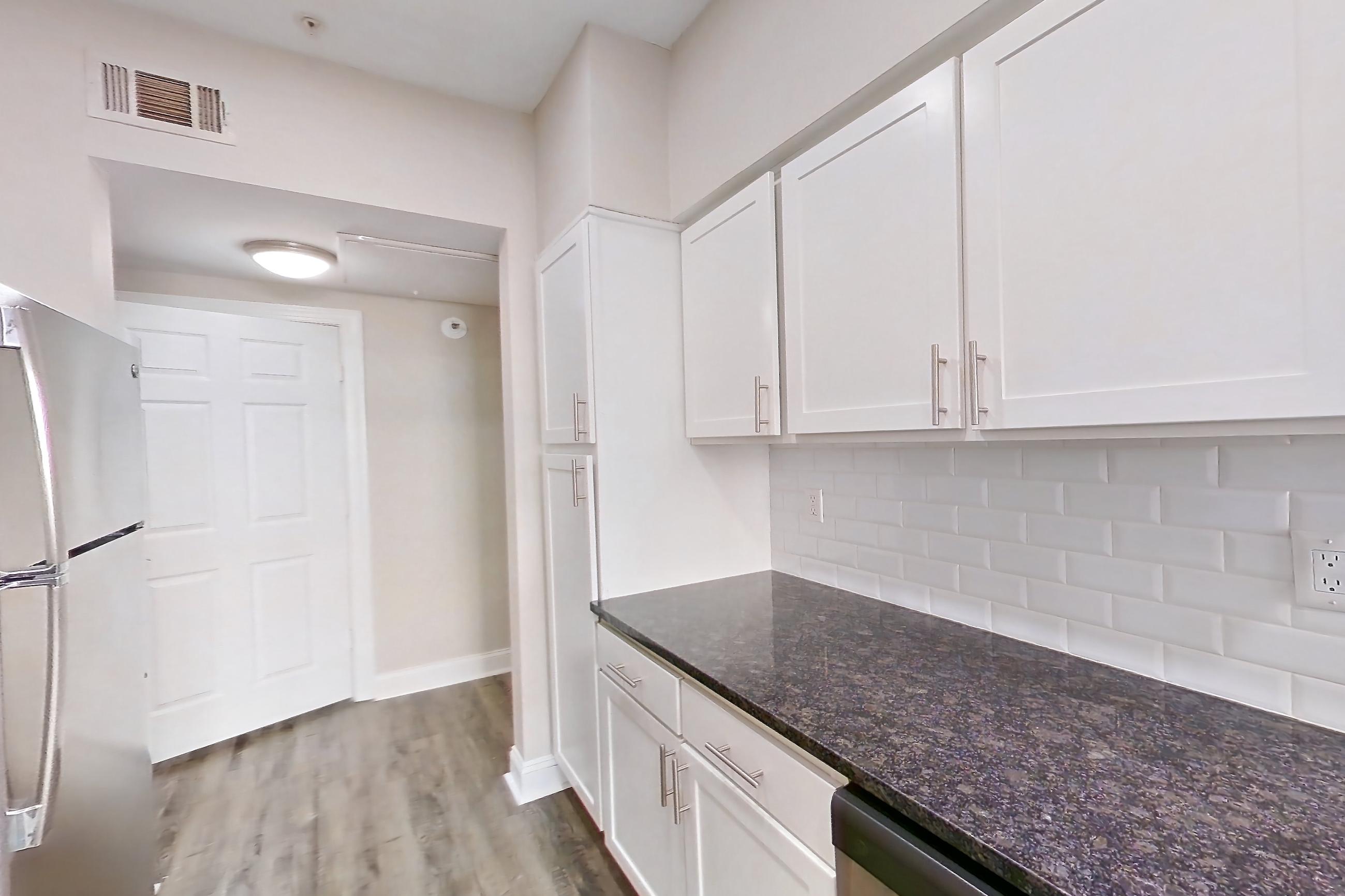 Kitchen with dark stone countertops, dishwasher, electric range, light countertops, oven/range, refrigerator, and stainless steel appliances, Apartment 6131 at Marq Perimeter