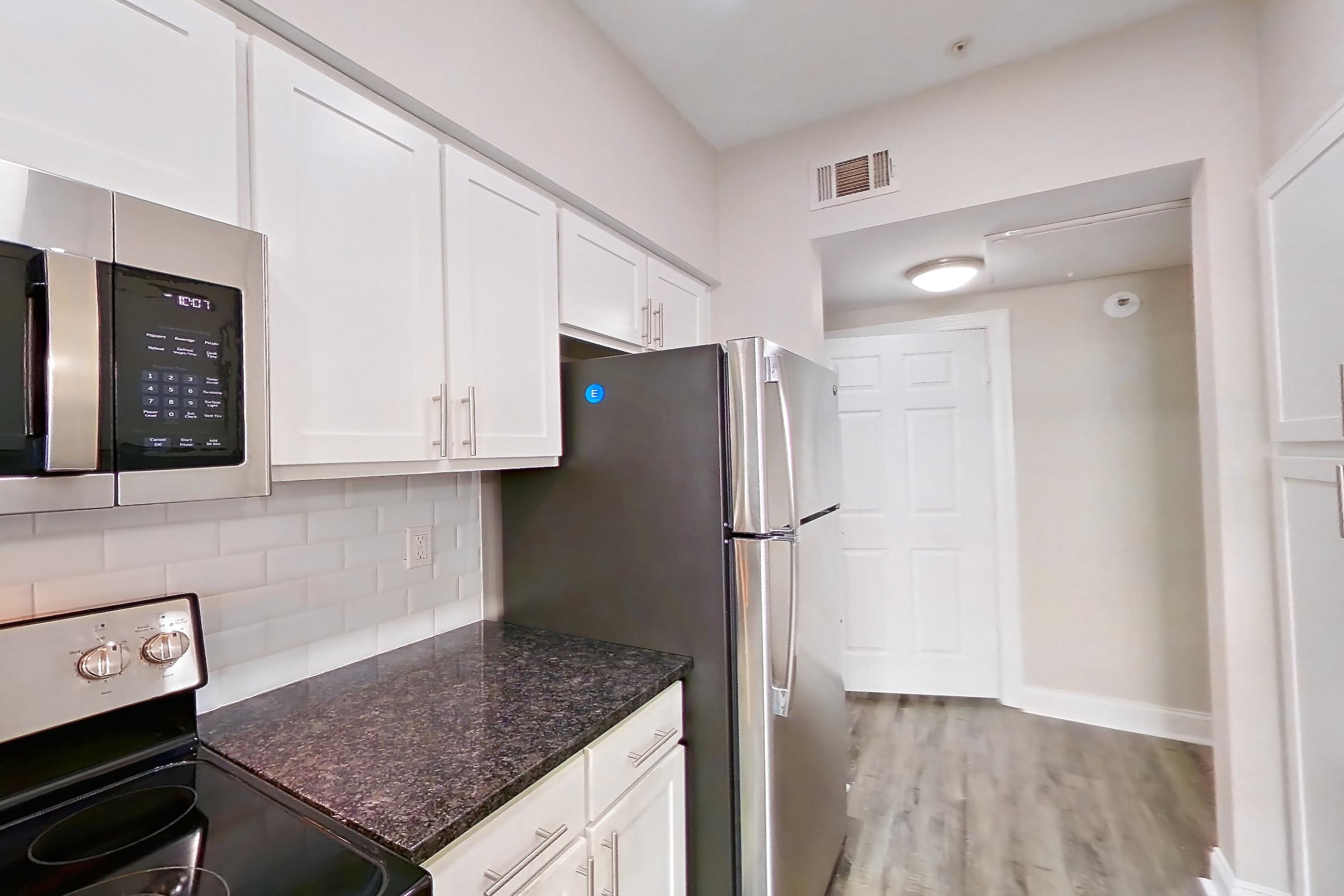 Kitchen with dark stone countertops, dishwasher, electric range, light countertops, oven/range, refrigerator, and stainless steel appliances, Apartment 6131 at Marq Perimeter