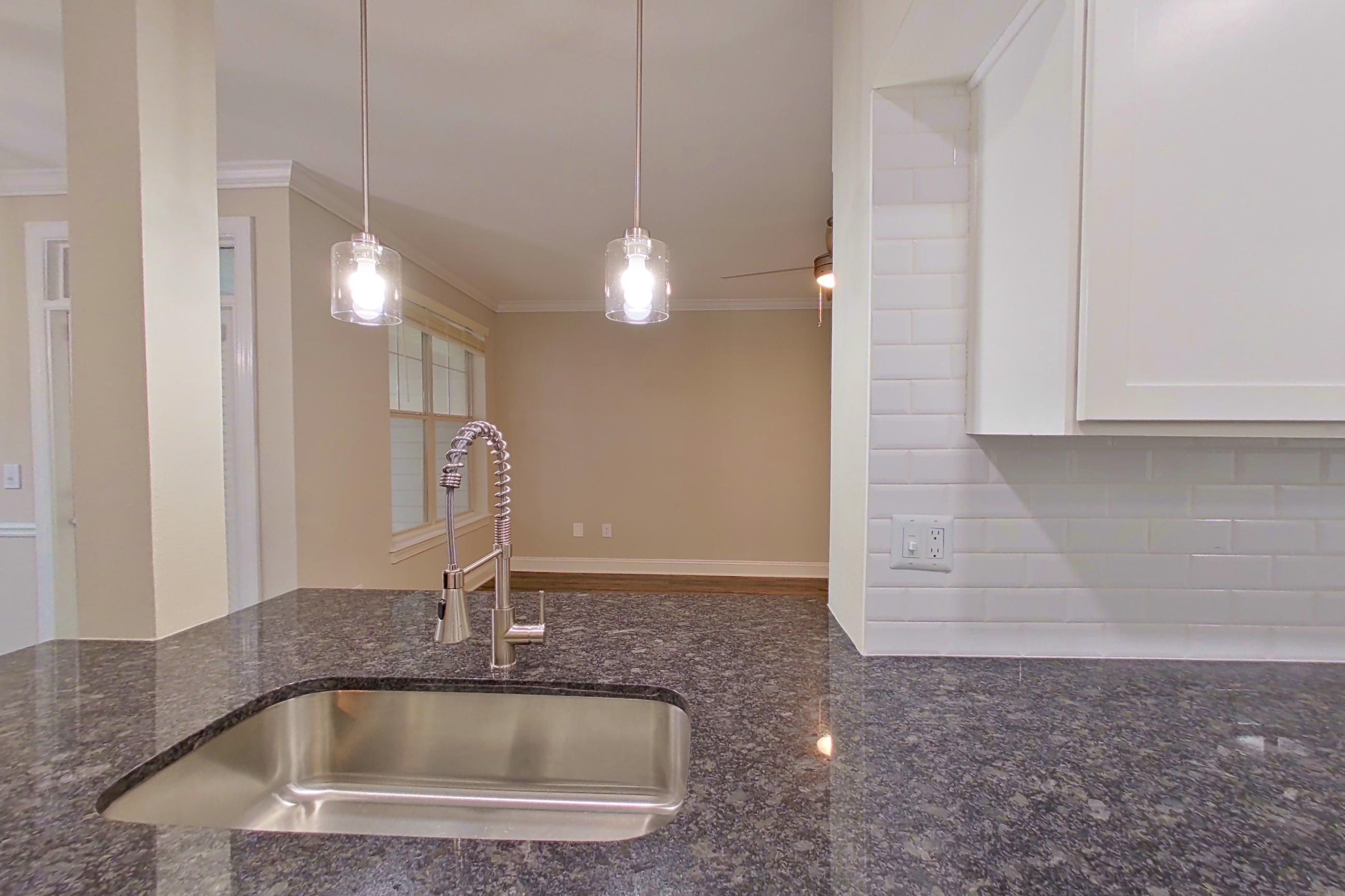 Kitchen with dark stone countertops, dishwasher, electric range, light countertops, light wood-finish flooring, microwave, oven/range, refrigerator, and stainless steel appliances, Apartment 6134 at Marq Perimeter