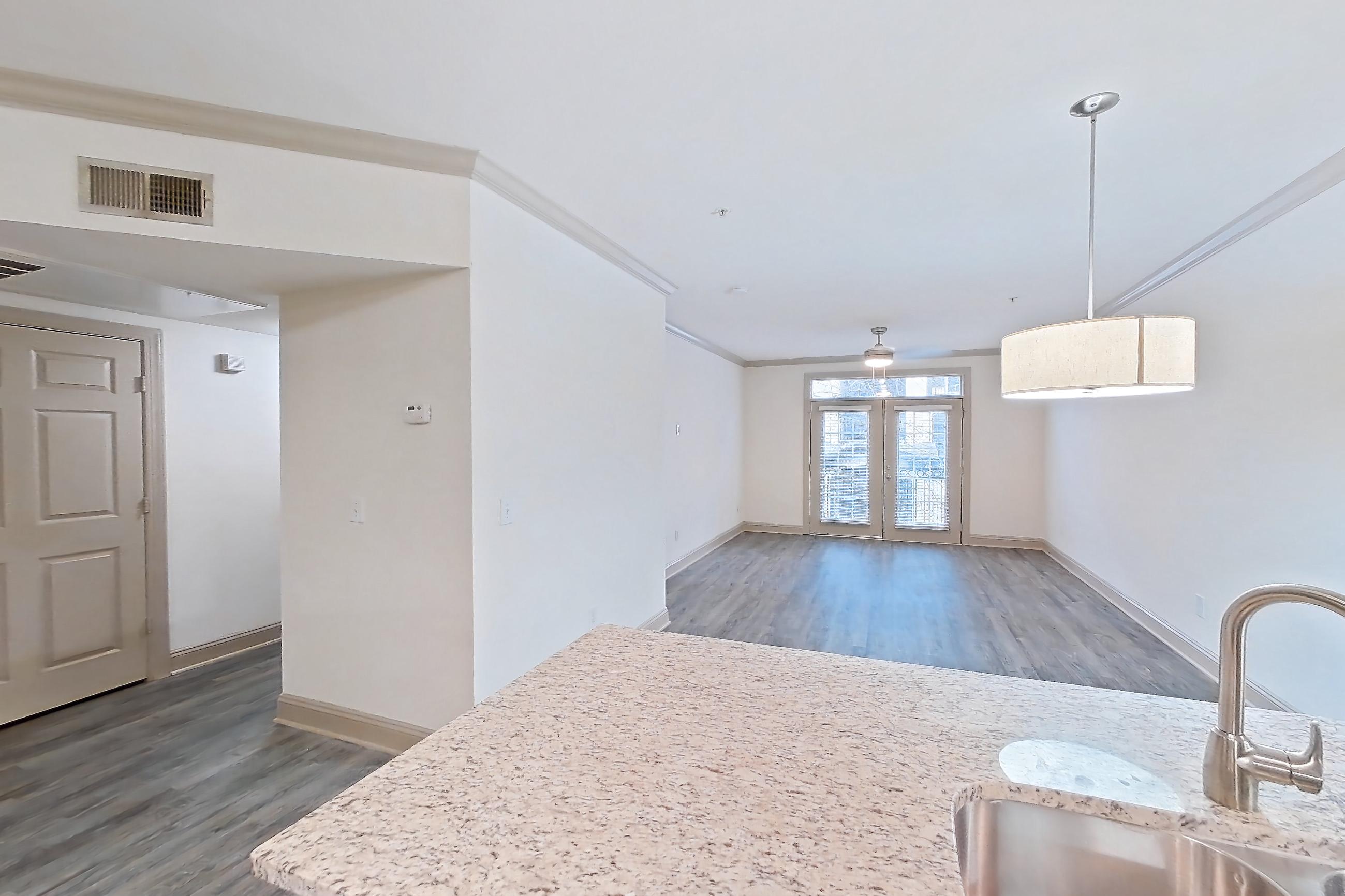 Kitchen with dark wood-finish flooring, dishwasher, electric range, light countertops, light stone countertops, light wood-finish flooring, microwave, oven/range, refrigerator, and stainless steel appliances, Apartment 6203 at Marq Perimeter