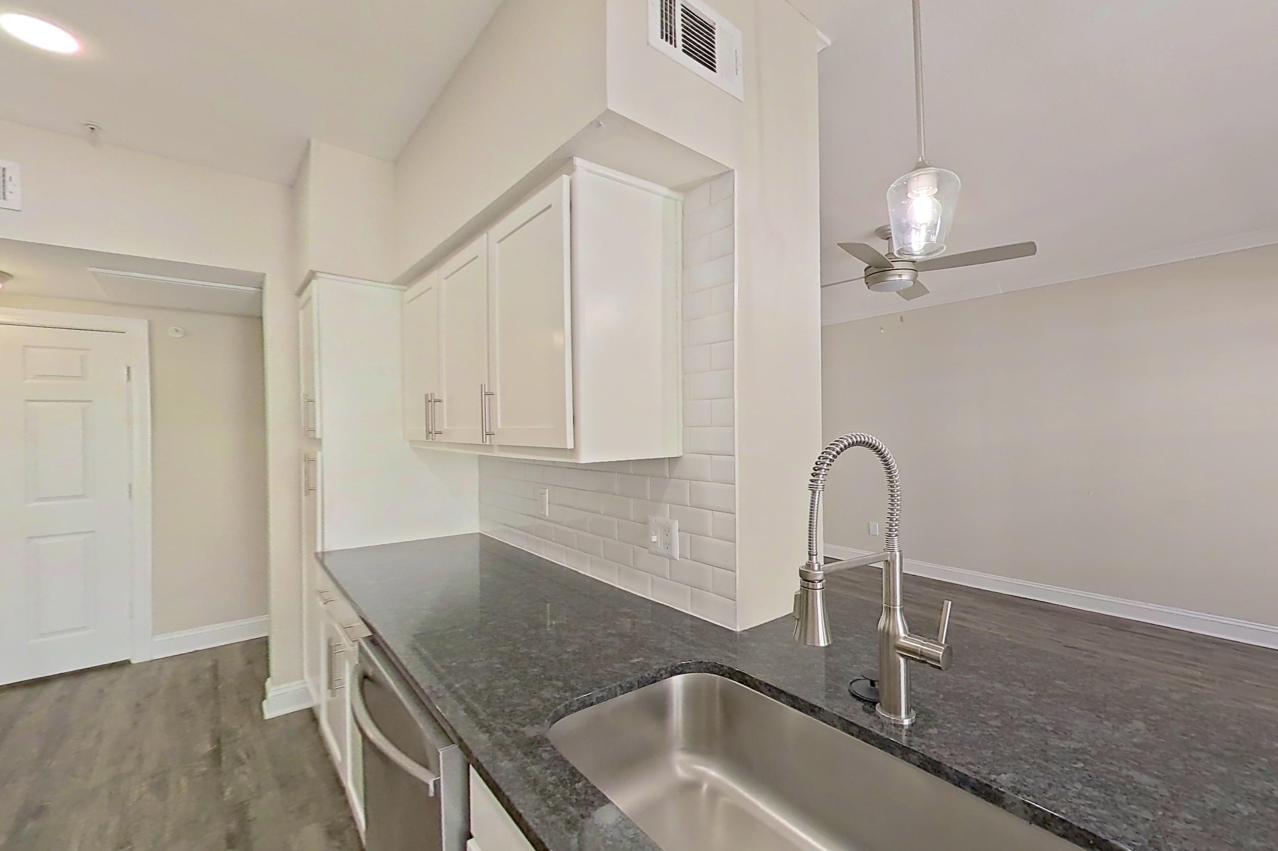 Kitchen with dark stone countertops, dishwasher, electric range, light countertops, light wood-finish flooring, oven/range, and stainless steel appliances, Apartment 6222 at Marq Perimeter