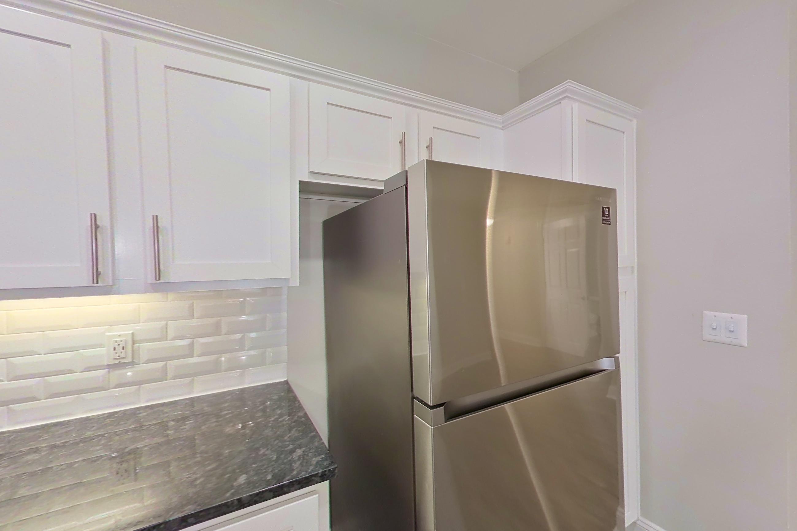 Kitchen with dark stone countertops, dishwasher, electric range, light countertops, microwave, oven/range, refrigerator, and stainless steel appliances, Apartment 6303 at Marq Perimeter