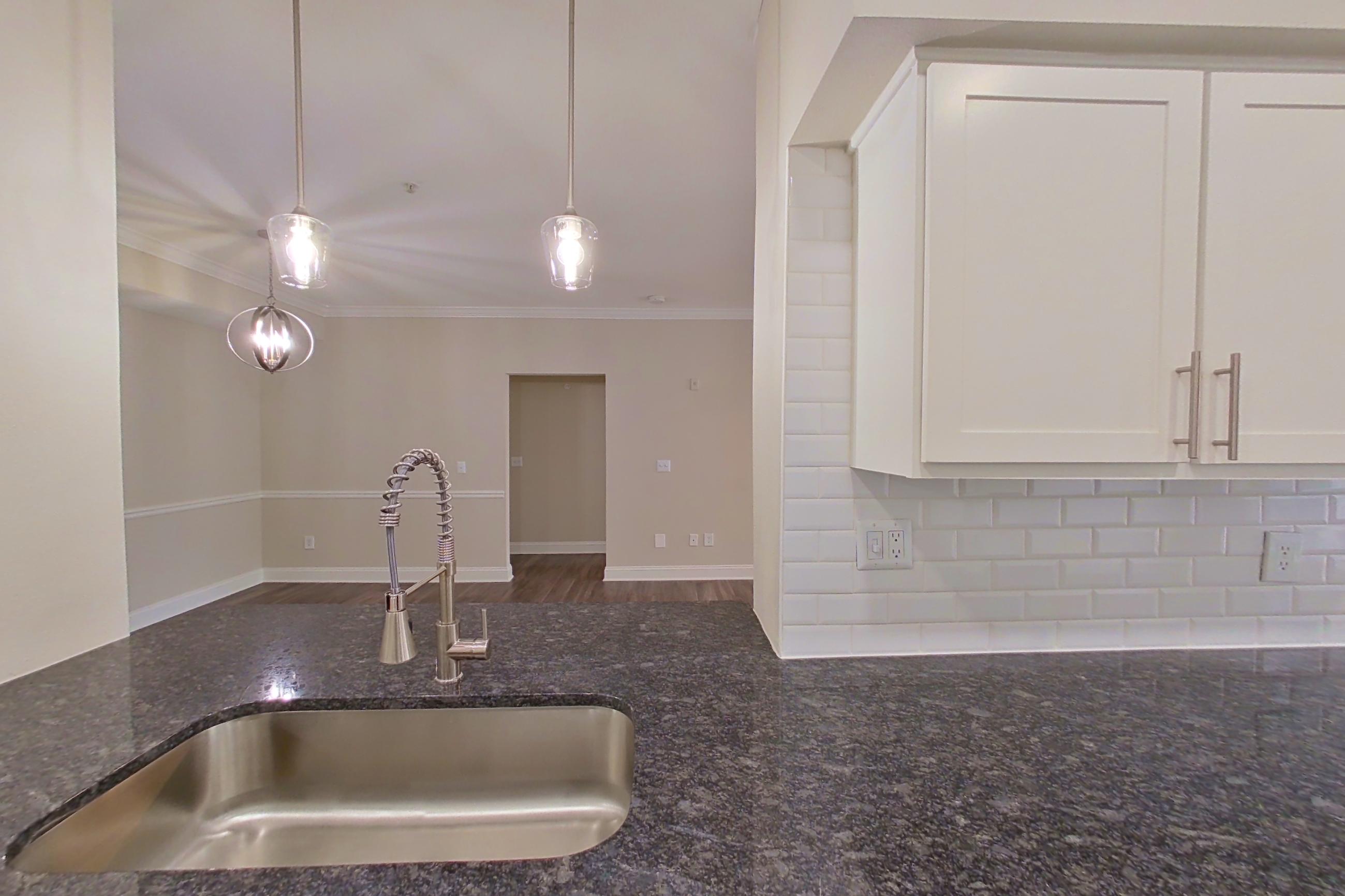 Kitchen with dark stone countertops, dark wood-finish flooring, dishwasher, electric range, light countertops, microwave, oven/range, refrigerator, and stainless steel appliances, Apartment 6313 at Marq Perimeter