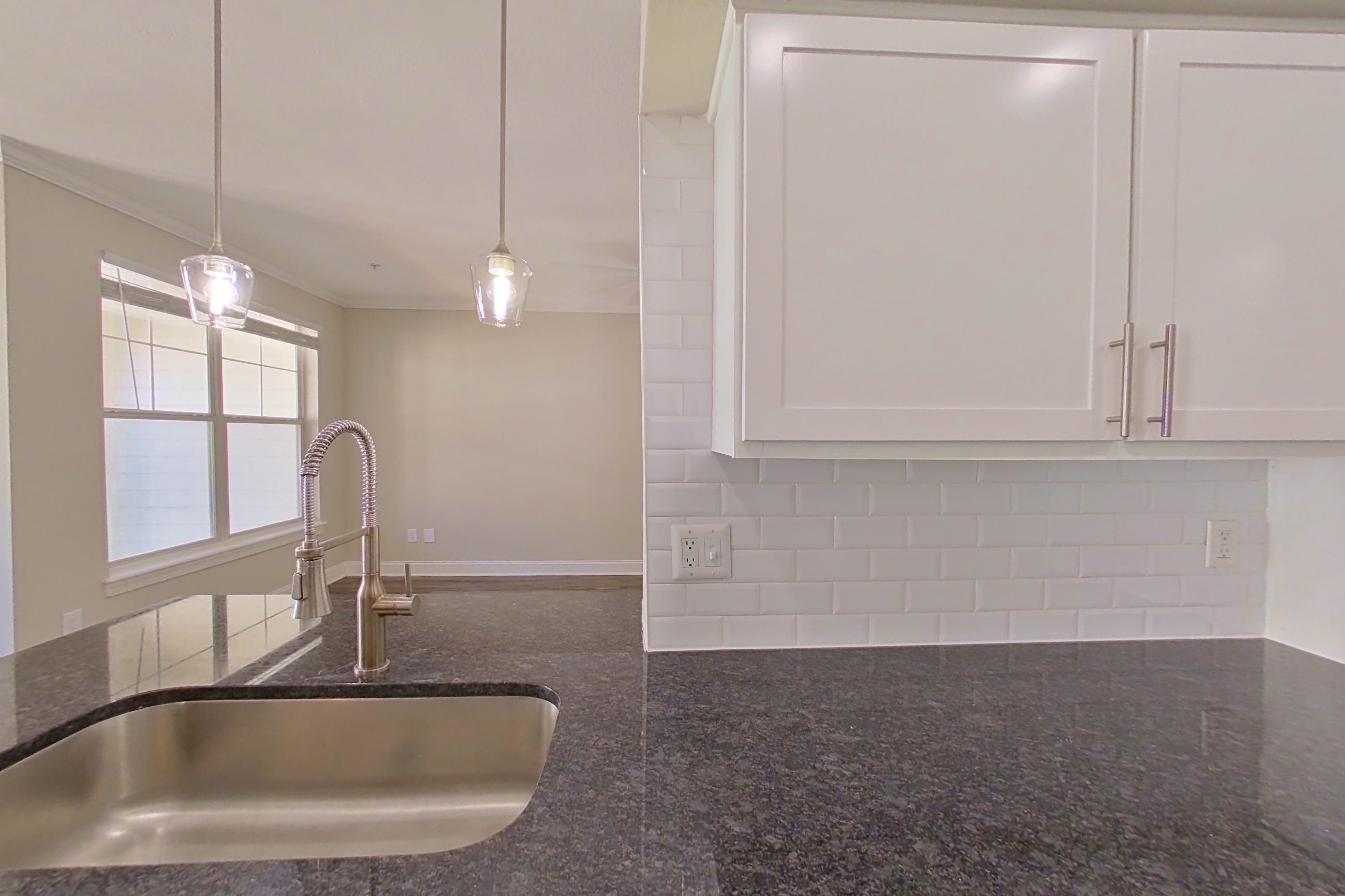 Kitchen with dark stone countertops, dark wood-finish flooring, dishwasher, electric range, light countertops, light wood-finish flooring, oven/range, refrigerator, and stainless steel appliances, Apartment 6320 at Marq Perimeter