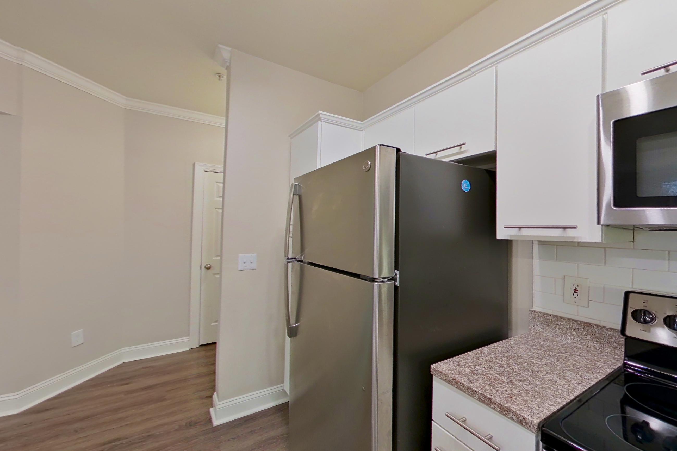 Kitchen with dishwasher, electric range, light countertops, light stone countertops, microwave, oven/range, refrigerator, and stainless steel appliances, Apartment 6324 at Marq Perimeter