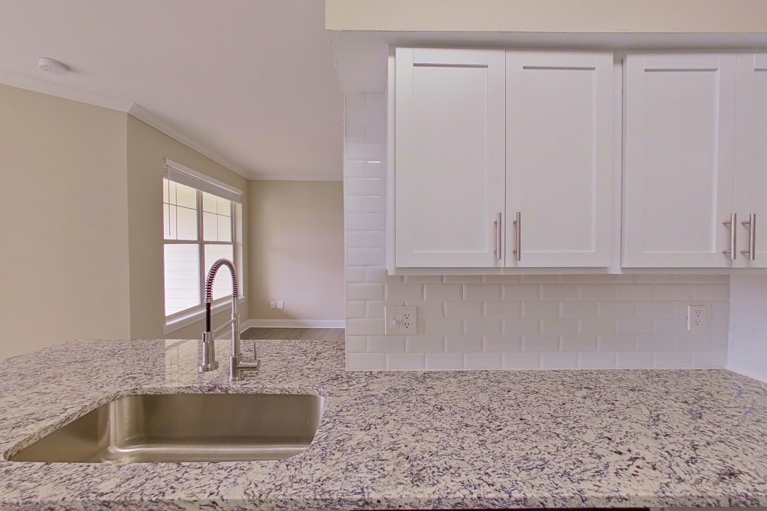 Kitchen with dishwasher, electric range, light stone countertops, light wood-finish flooring, oven/range, refrigerator, and stainless steel appliances, Apartment 6332 at Marq Perimeter