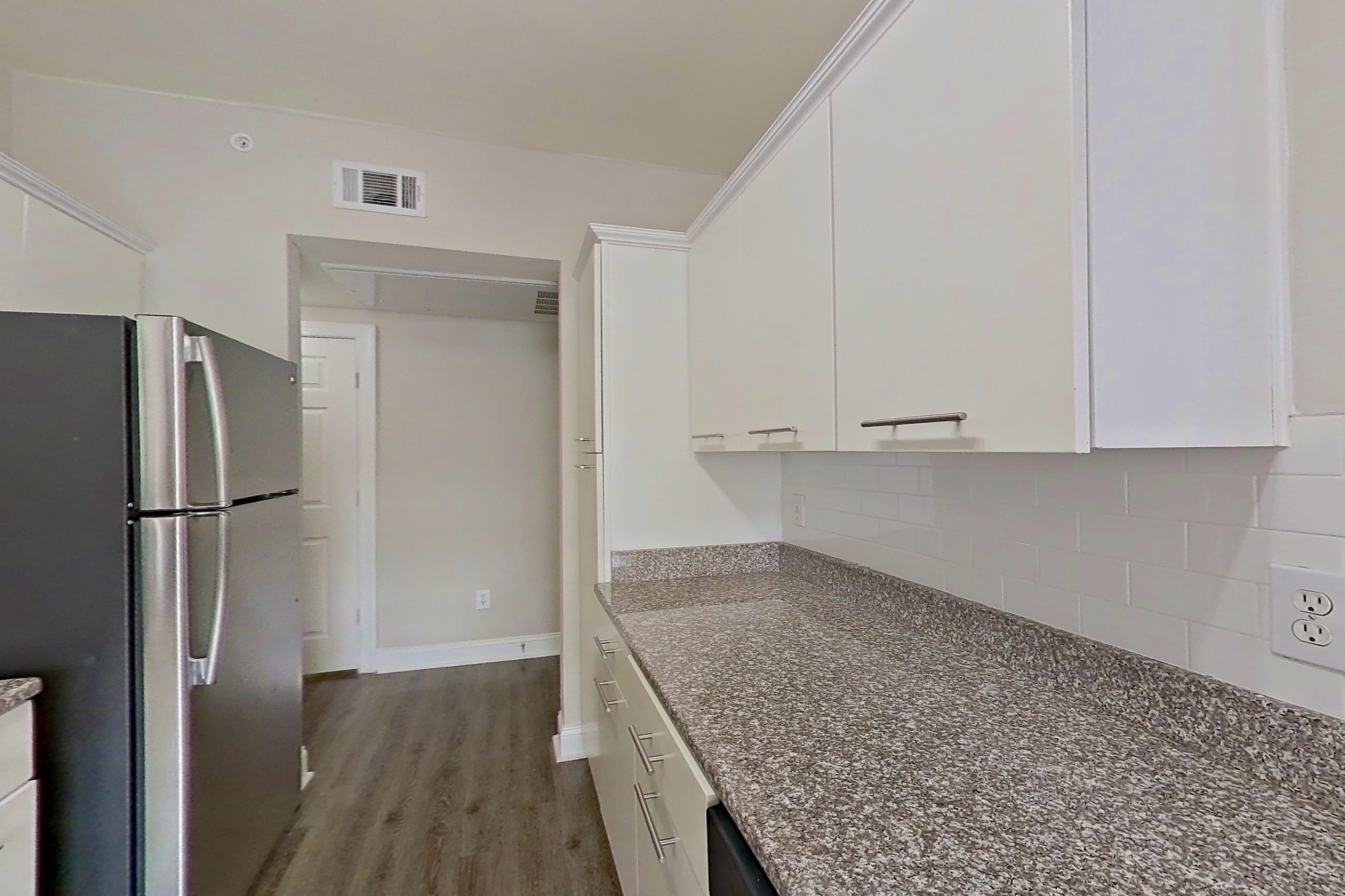Kitchen with dark stone countertops, electric range, light stone countertops, microwave, oven/range, refrigerator, and stainless steel appliances, Apartment 6419 at Marq Perimeter