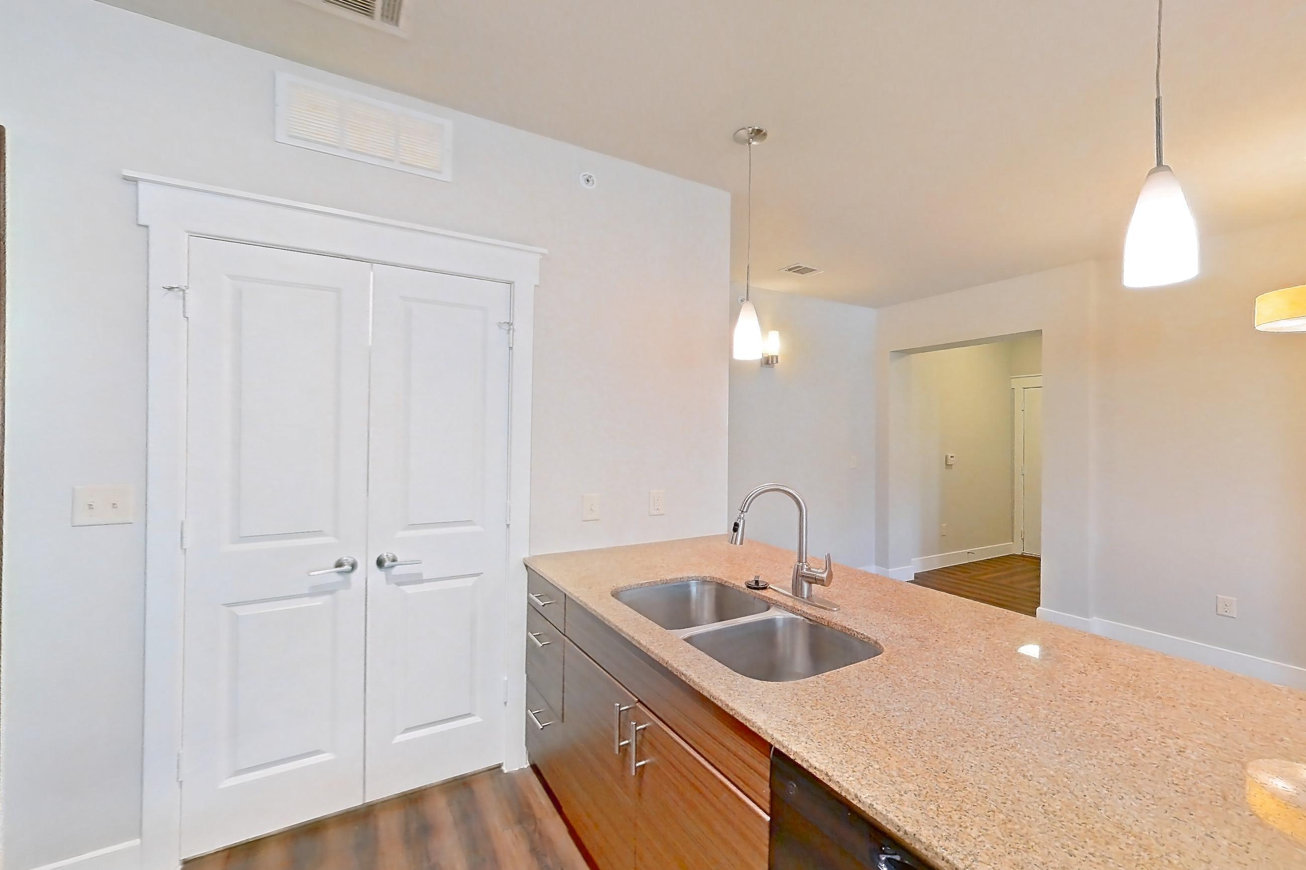 Kitchen with black appliances, dark wood-finish flooring, dishwasher, electric range, light countertops, light stone countertops, microwave, oven/range, and refrigerator, Apartment 04306 at Marquis Cresta Bella