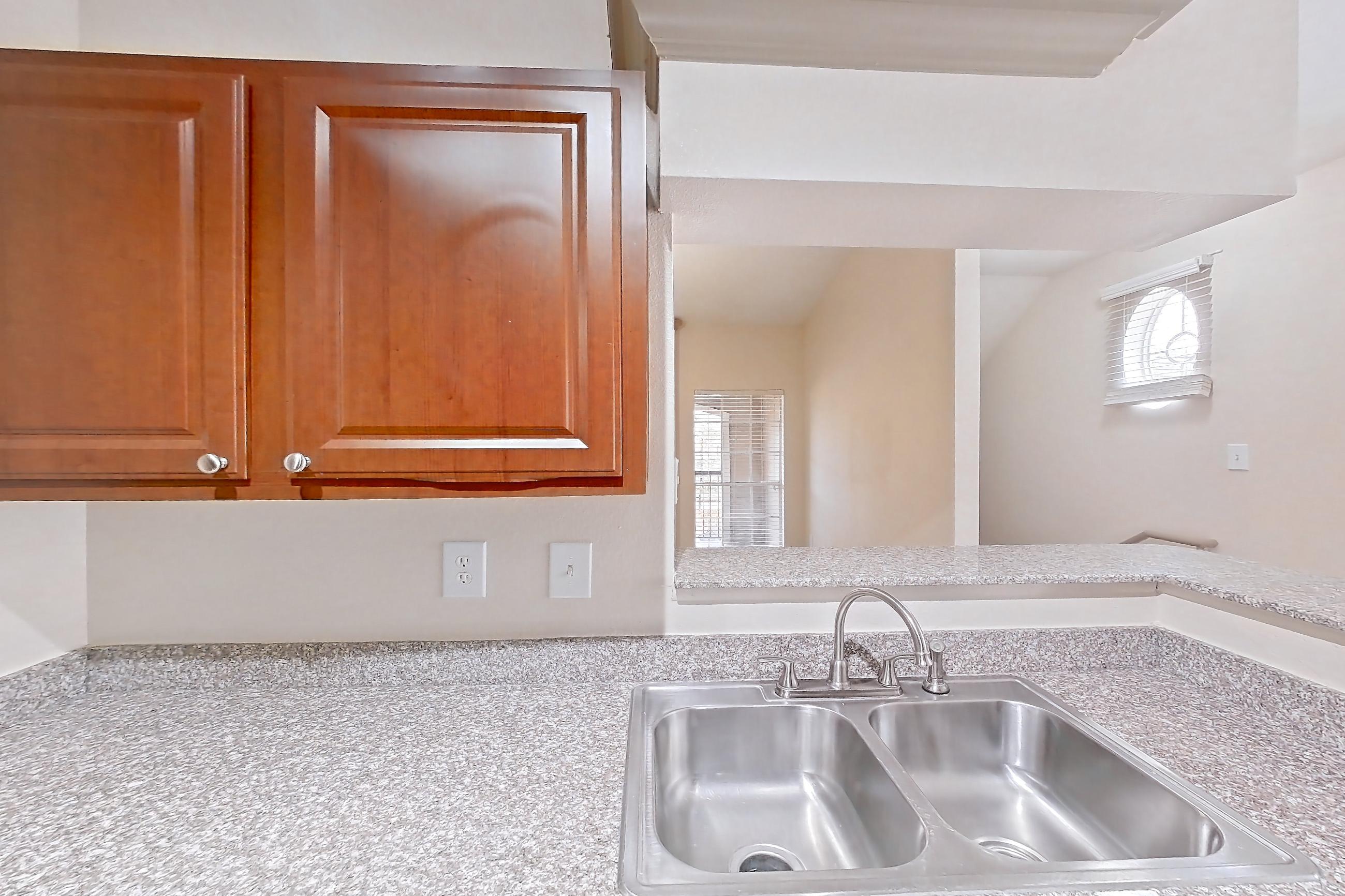 Kitchen with black appliances, dishwasher, electric range, in-unit laundry, light carpet, light countertops, light stone countertops, light wood-finish flooring, oven/range, refrigerator, and stainless steel appliances, Apartment 0425 at Marquis on Park Row
