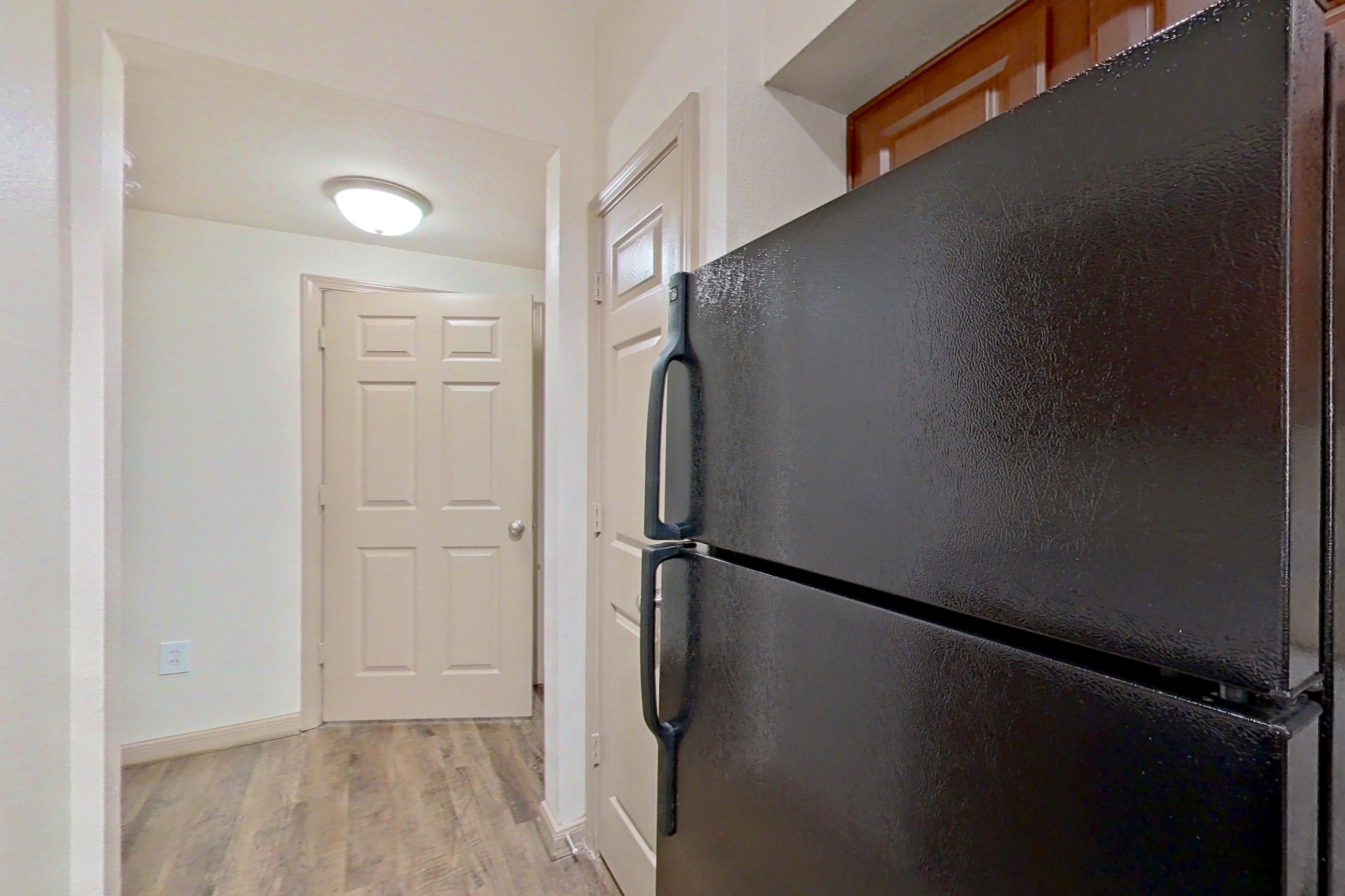 Kitchen with black appliances, dishwasher, electric range, light countertops, light stone countertops, light wood-finish flooring, microwave, oven/range, and refrigerator, Apartment 0618 at Marquis on Park Row