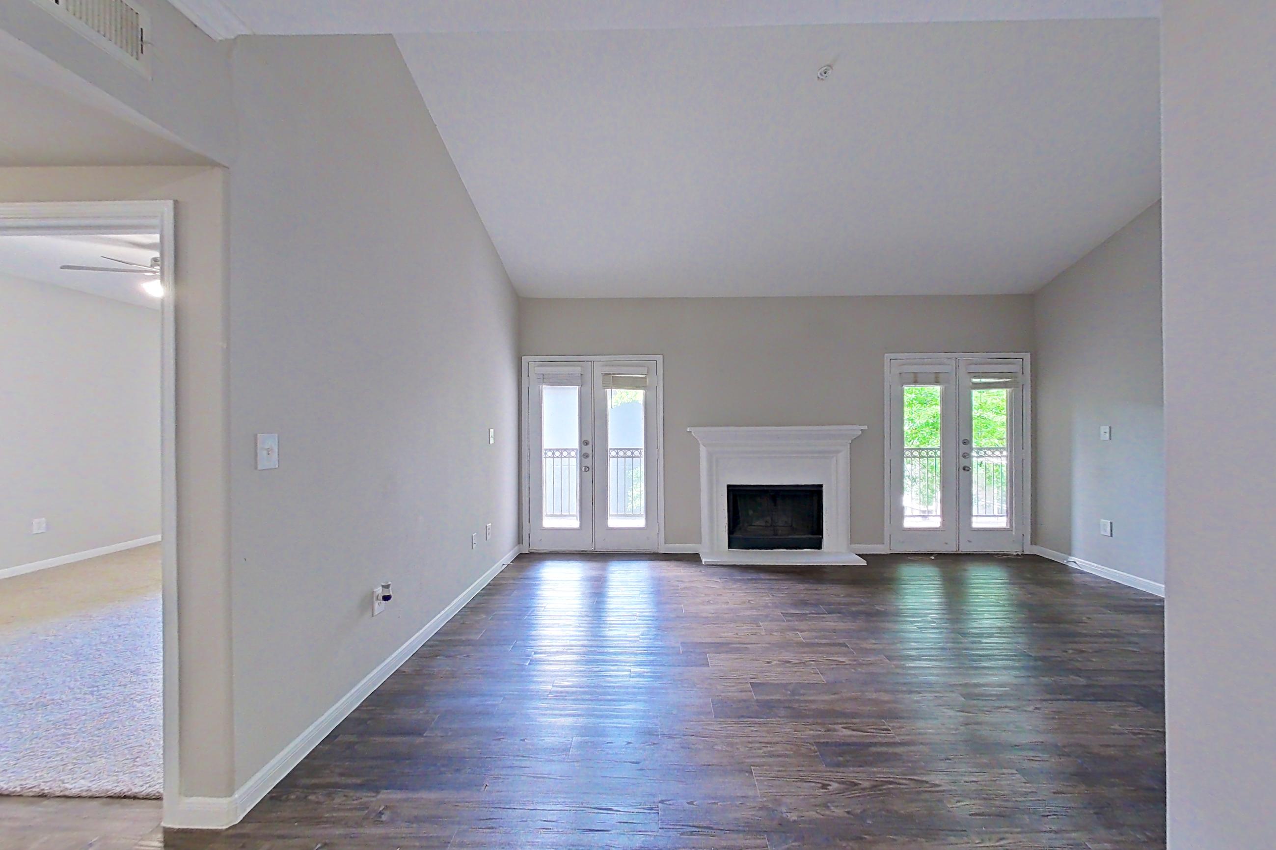 Dining room with dark wood-finish flooring, electric range, fireplace, light stone countertops, light wood-finish flooring, oven/range, refrigerator, and stainless steel appliances, Apartment 0233 at Marquis on Westheimer