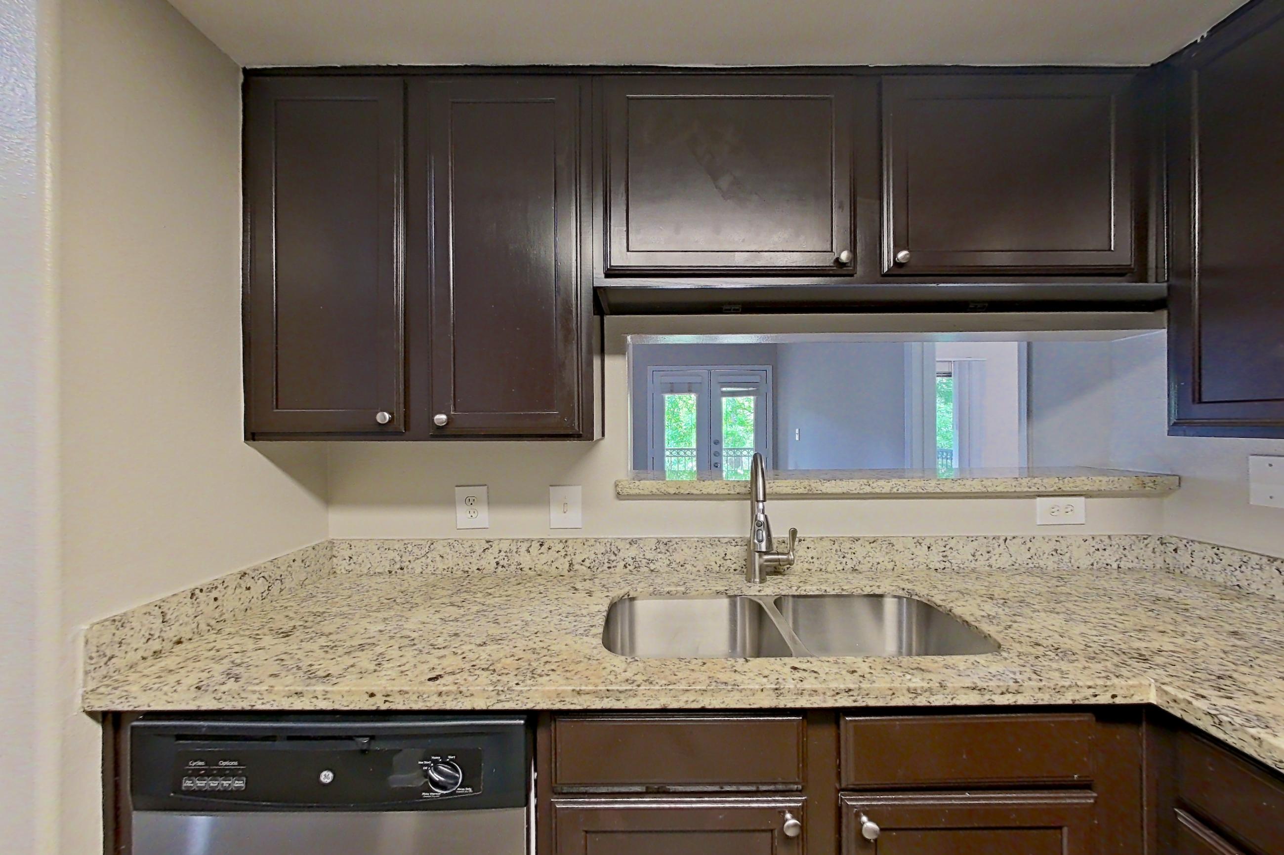 Kitchen with dark wood-finish flooring, dishwasher, electric range, light stone countertops, light wood-finish flooring, microwave, oven/range, and stainless steel appliances, Apartment 0233 at Marquis on Westheimer