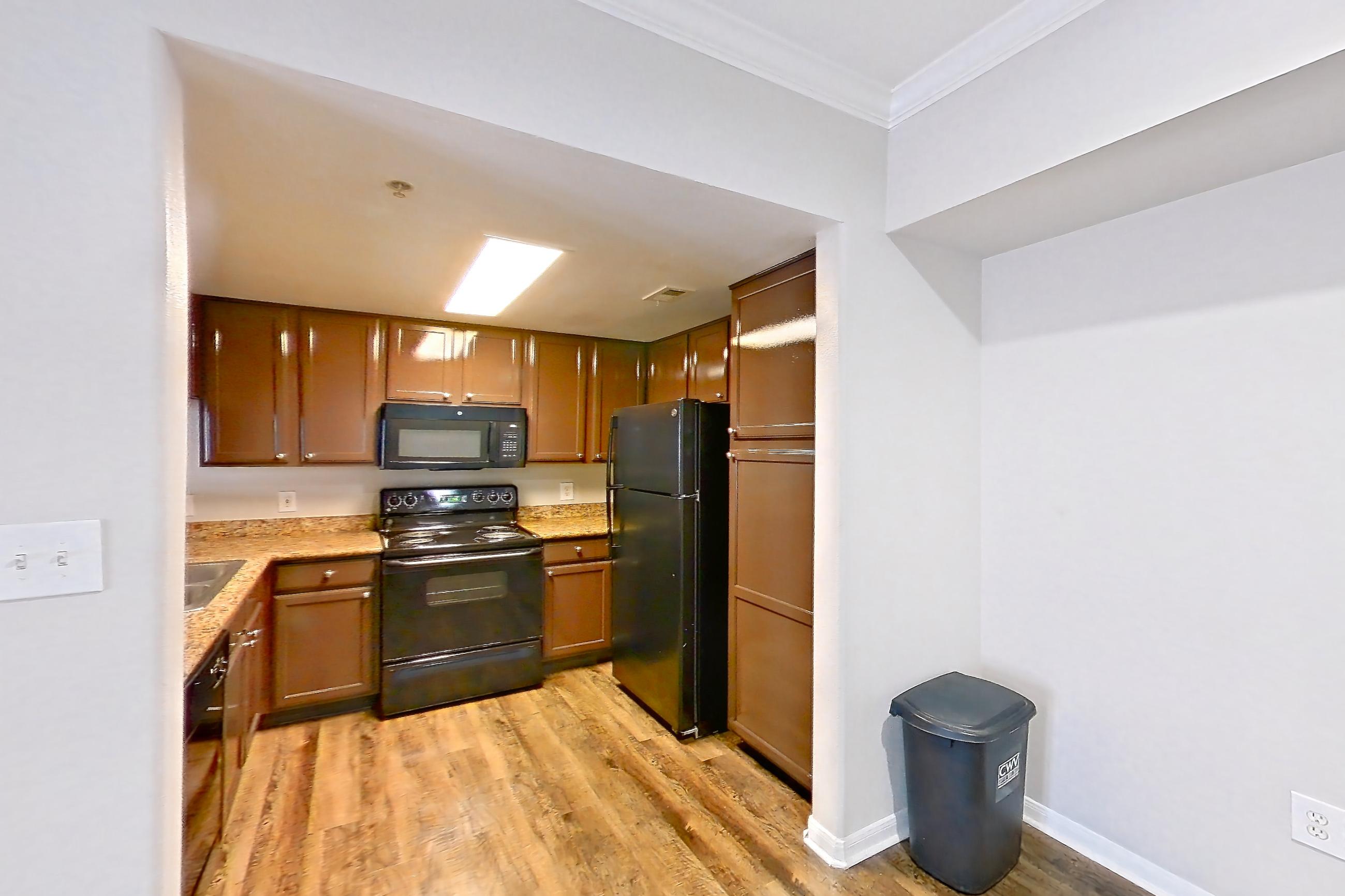 Dining room with black appliances, electric range, fireplace, light countertops, light stone countertops, light wood-finish flooring, oven/range, and refrigerator, Apartment 0323 at Marquis on Westheimer