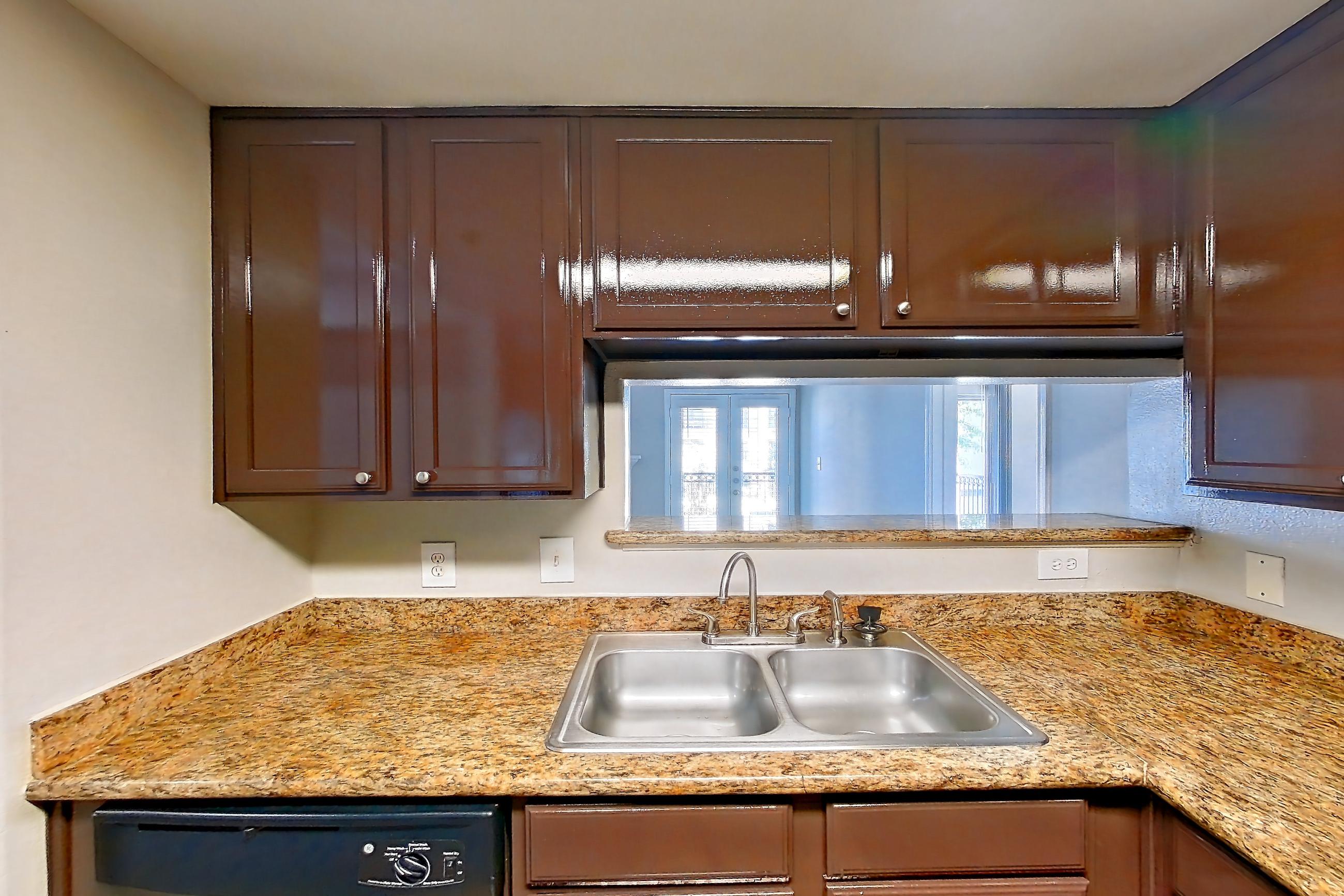 Kitchen with black appliances, cooktop, dark wood-finish flooring, dishwasher, electric range, light countertops, light stone countertops, light wood-finish flooring, microwave, oven/range, and stainless steel appliances, Apartment 0323 at Marquis on Westheimer