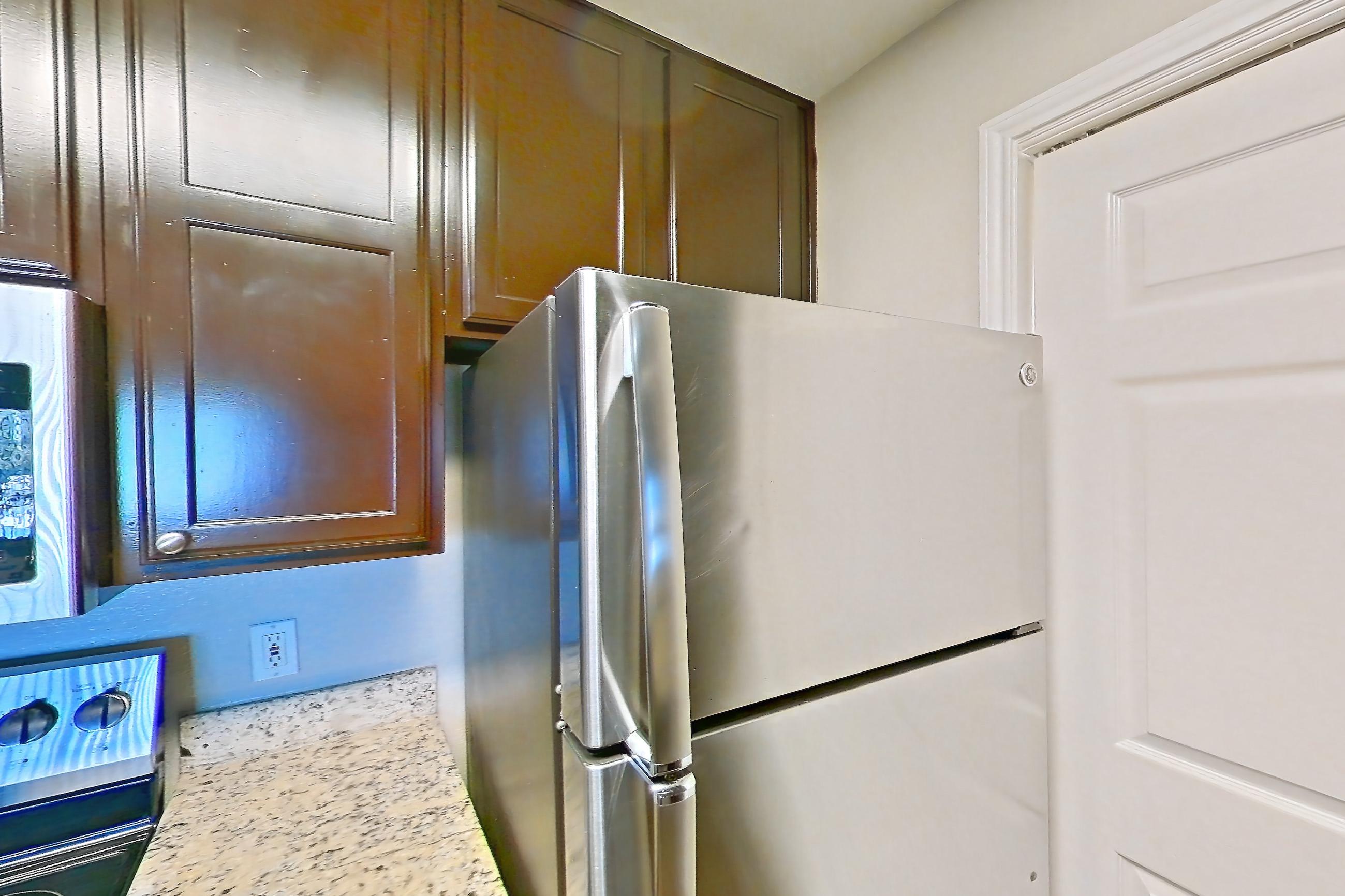 Kitchen with dishwasher, electric range, light stone countertops, light wood-finish flooring, microwave, oven/range, refrigerator, and stainless steel appliances, Apartment 0335 at Marquis on Westheimer