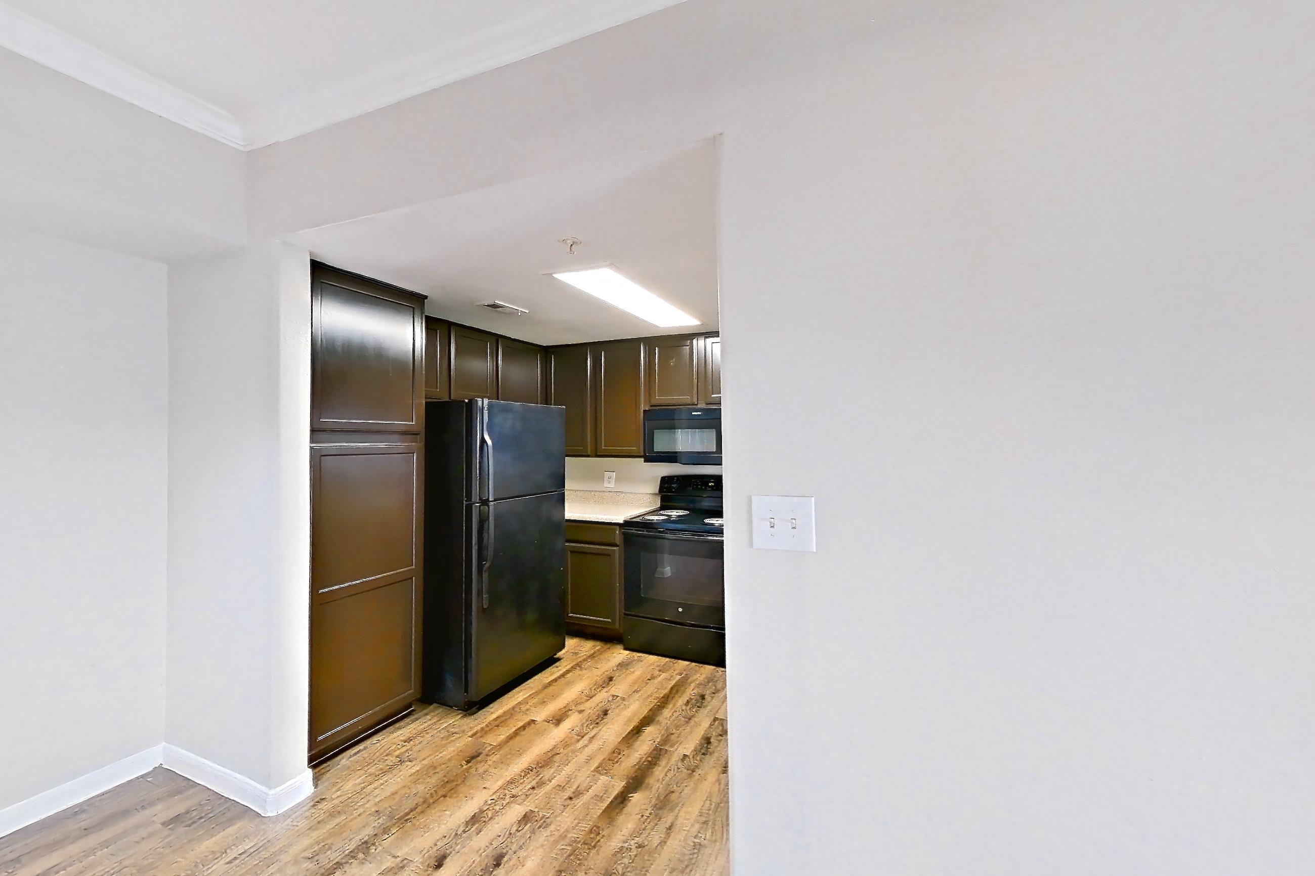 Dining room with black appliances, dark wood-finish flooring, electric range, fireplace, light stone countertops, light wood-finish flooring, oven/range, and refrigerator, Apartment 0336 at Marquis on Westheimer