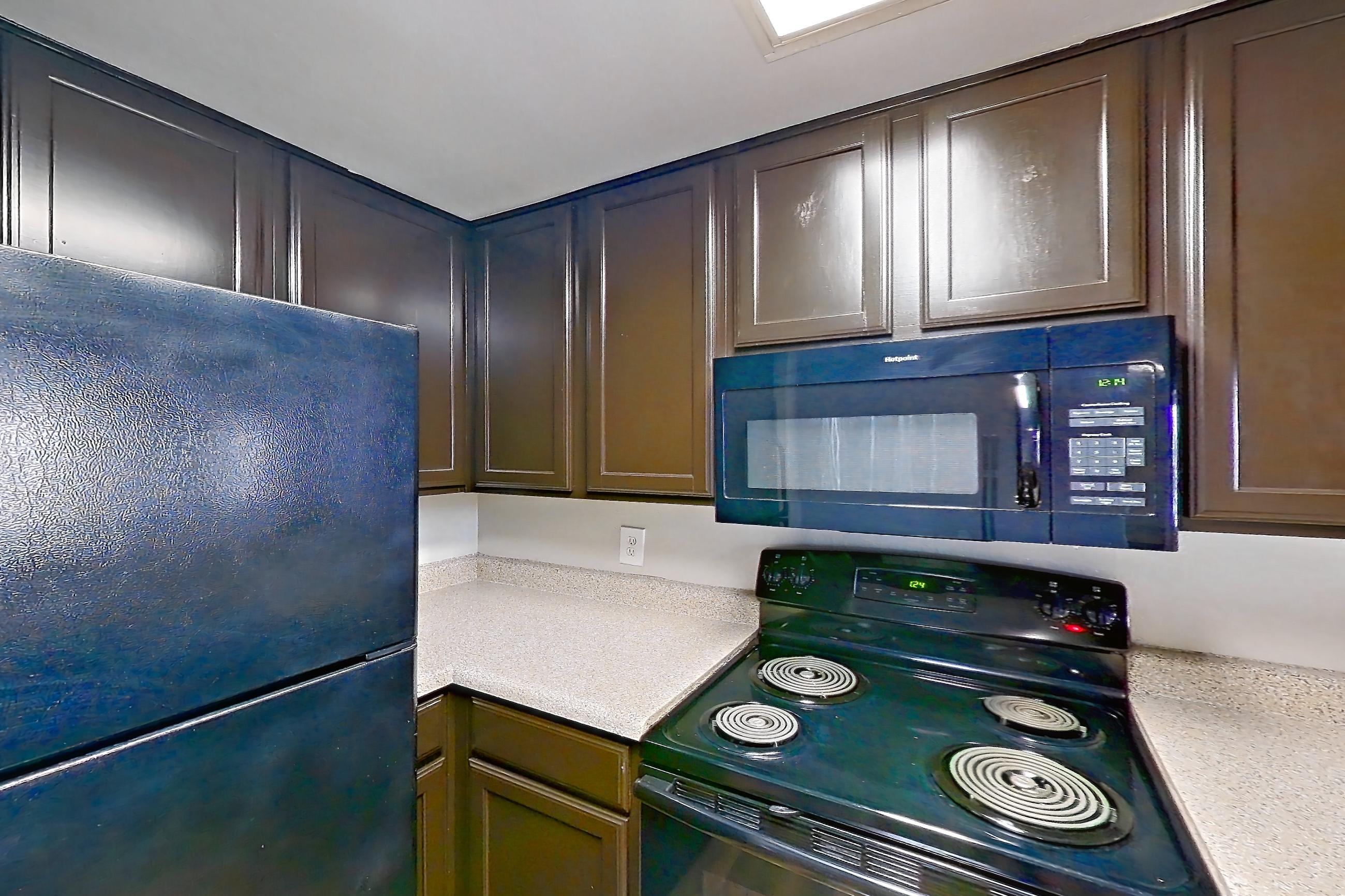 Kitchen with black appliances, dishwasher, electric range, light stone countertops, light wood-finish flooring, microwave, and oven/range, Apartment 0336 at Marquis on Westheimer