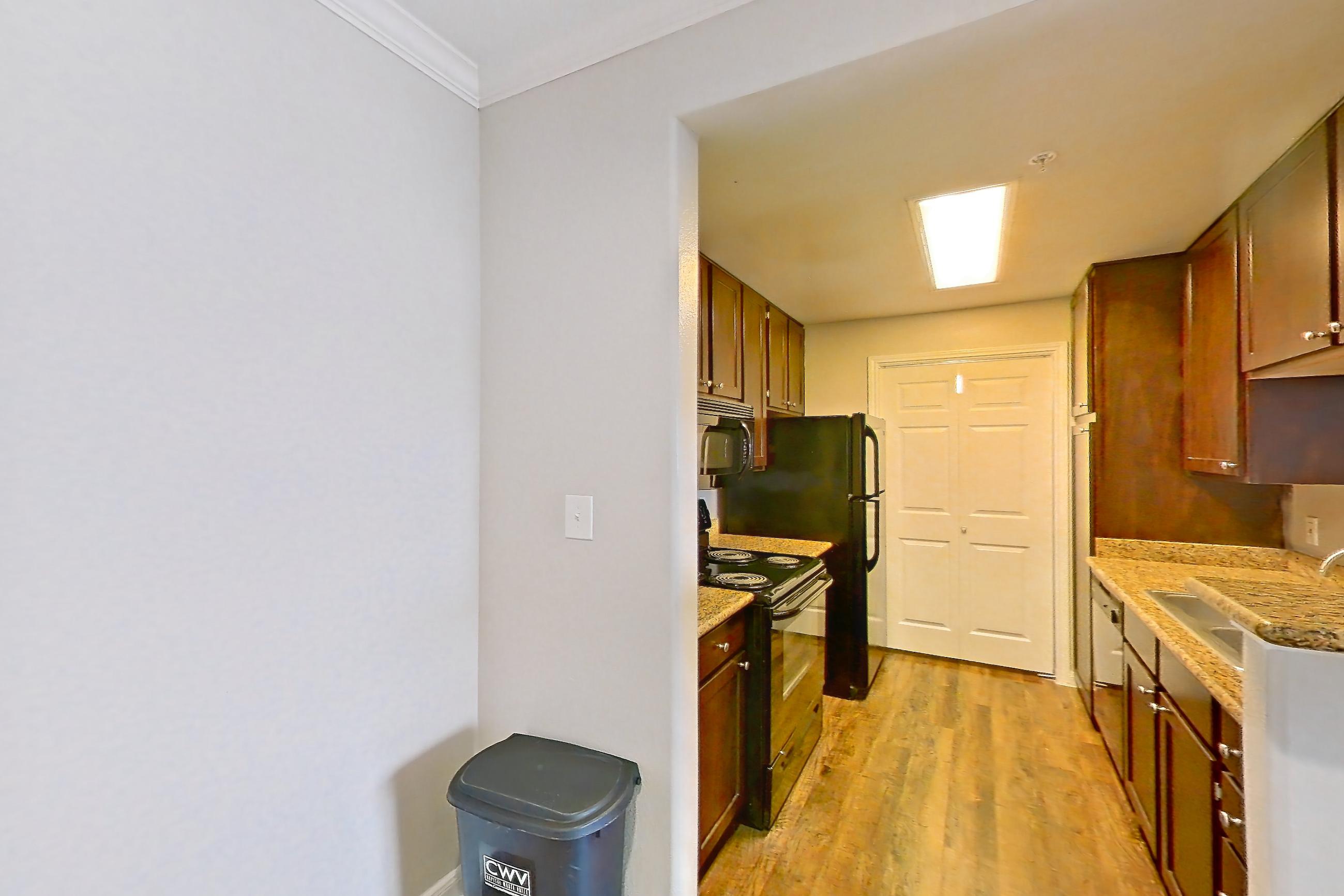 Dining room with dark wood-finish flooring, electric range, light countertops, light stone countertops, and light wood-finish flooring, Apartment 0425 at Marquis on Westheimer
