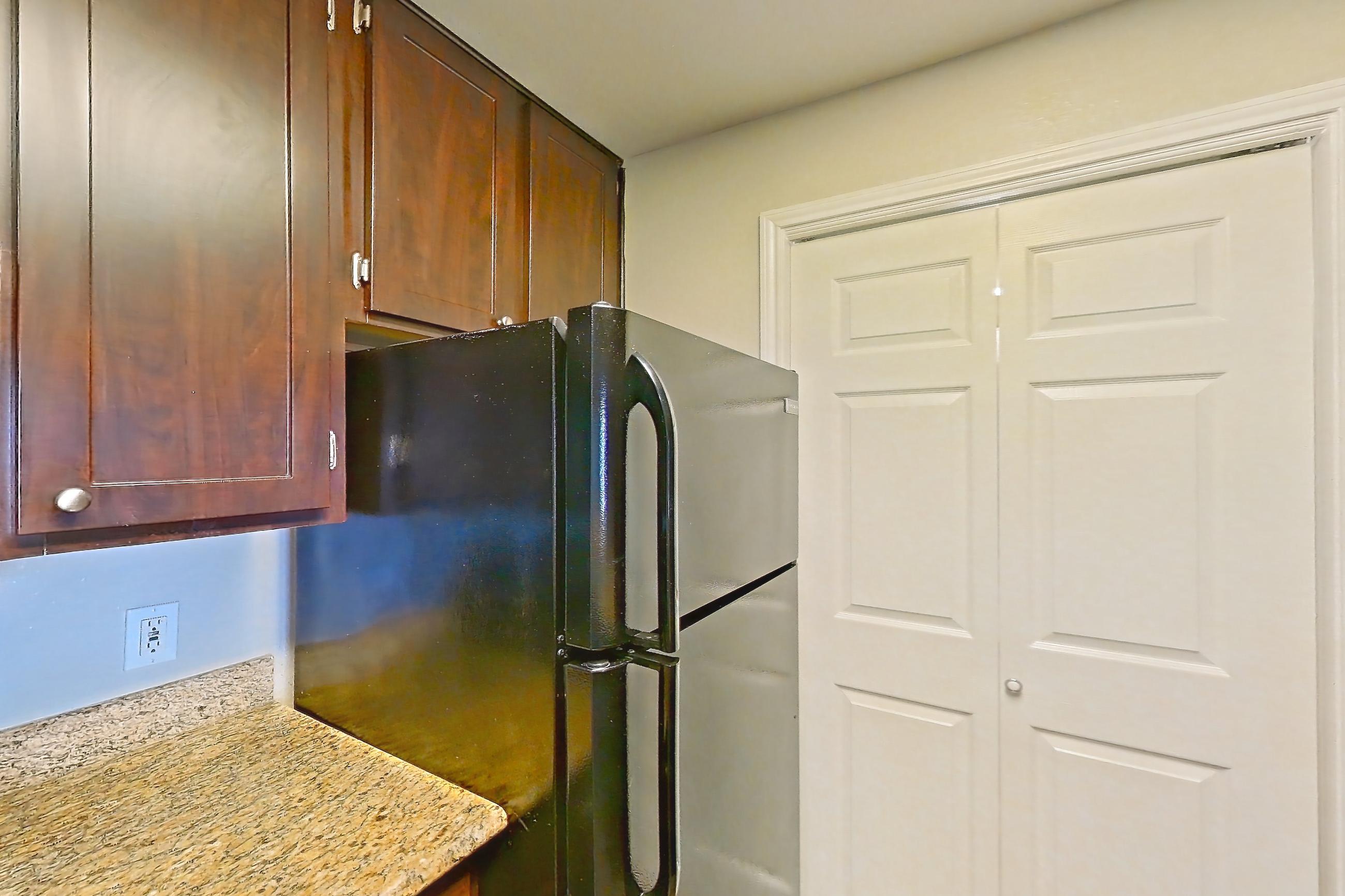 Kitchen with black appliances, dishwasher, electric range, light stone countertops, light wood-finish flooring, oven/range, and refrigerator, Apartment 0425 at Marquis on Westheimer