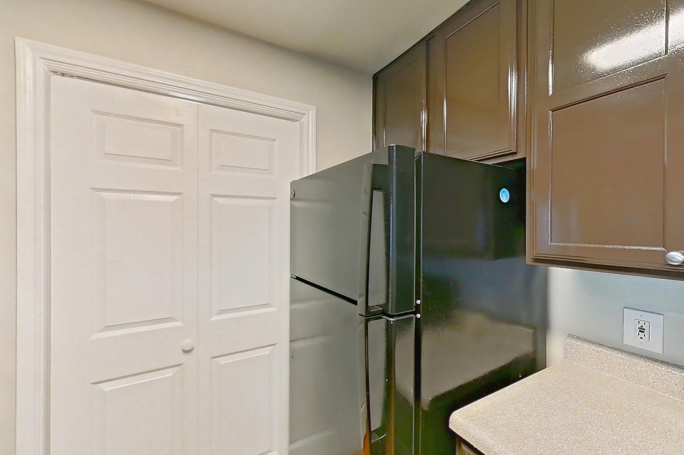 Kitchen with black appliances, dishwasher, electric range, light stone countertops, light wood-finish flooring, oven/range, refrigerator, and stainless steel appliances, Apartment 0428 at Marquis on Westheimer