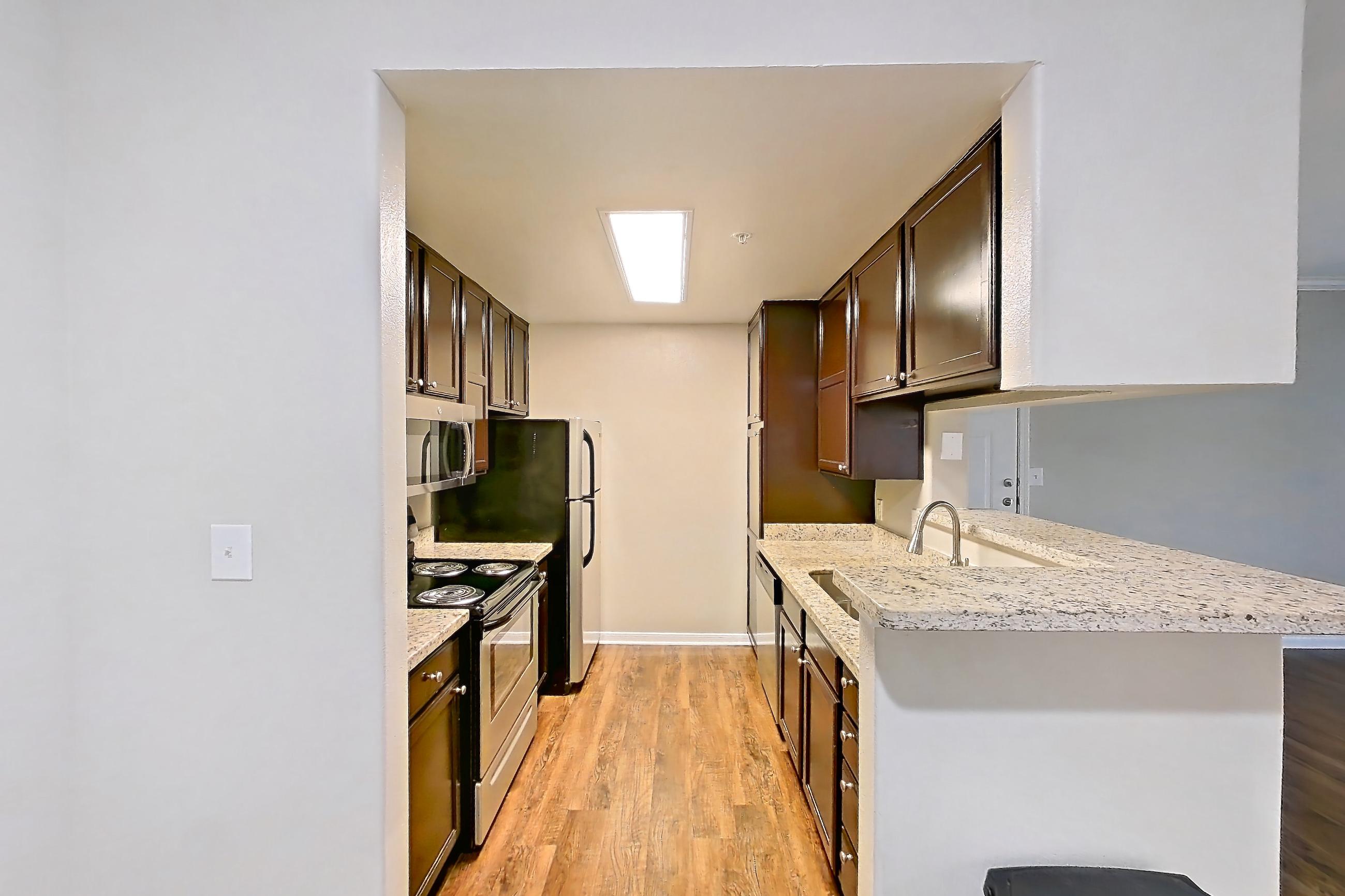 Dining room with dark carpet, dark wood-finish flooring, dishwasher, electric range, fireplace, light stone countertops, light wood-finish flooring, oven/range, refrigerator, and stainless steel appliances, Apartment 0433 at Marquis on Westheimer