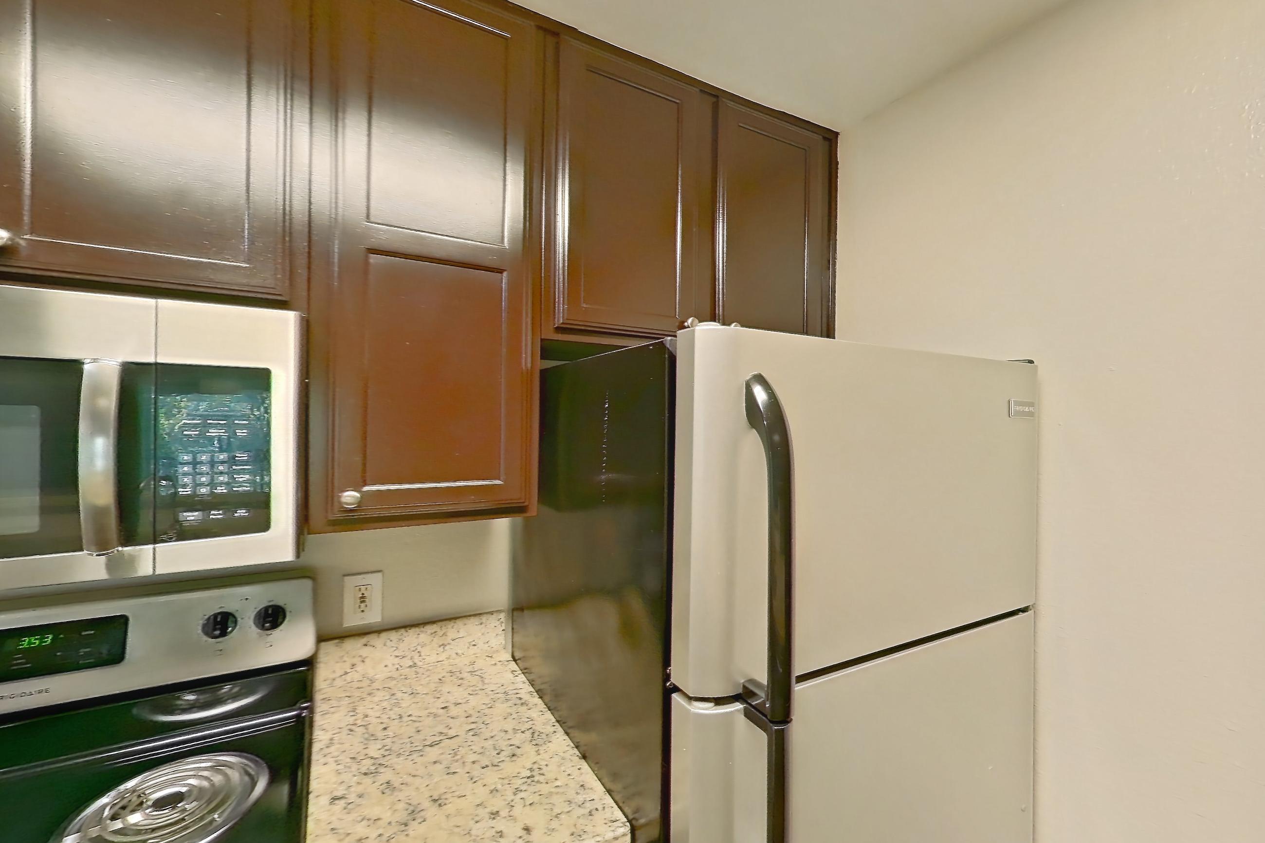 Kitchen with dishwasher, electric range, light stone countertops, light wood-finish flooring, microwave, oven/range, refrigerator, stainless steel appliances, and white appliances, Apartment 0433 at Marquis on Westheimer