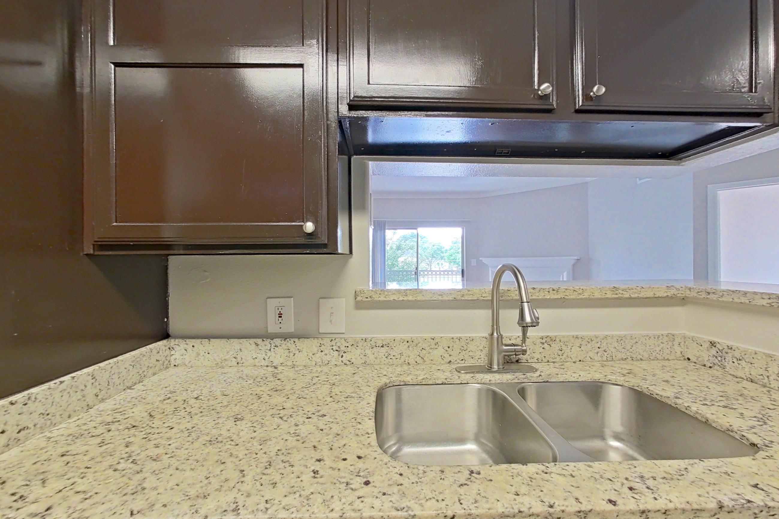 Kitchen with dark wood-finish flooring, dishwasher, electric range, light stone countertops, refrigerator, and stainless steel appliances, Apartment 0525 at Marquis on Westheimer