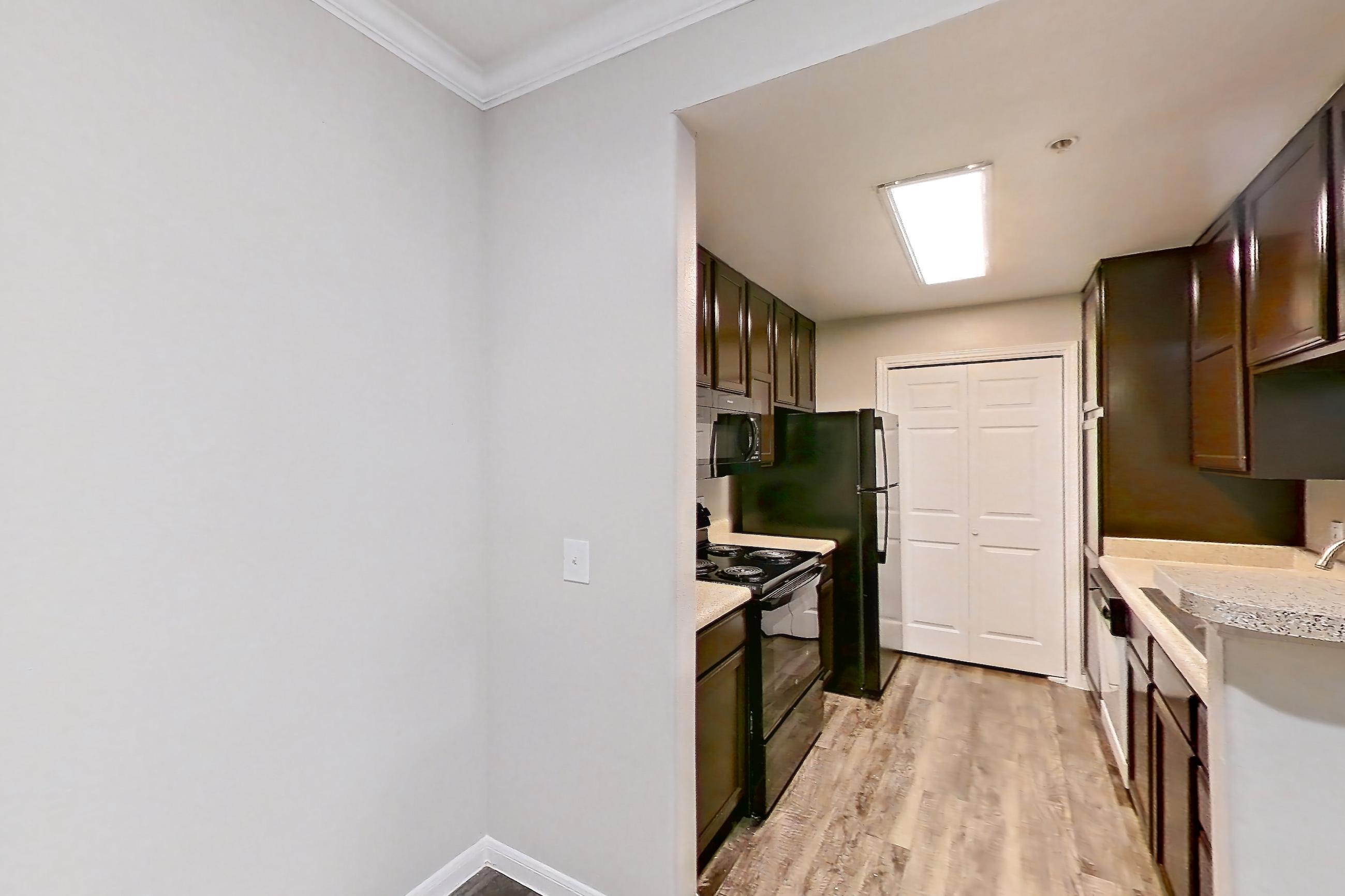Dining room with black appliances, dark wood-finish flooring, electric range, light countertops, light wood-finish flooring, oven/range, and refrigerator, Apartment 0615 at Marquis on Westheimer
