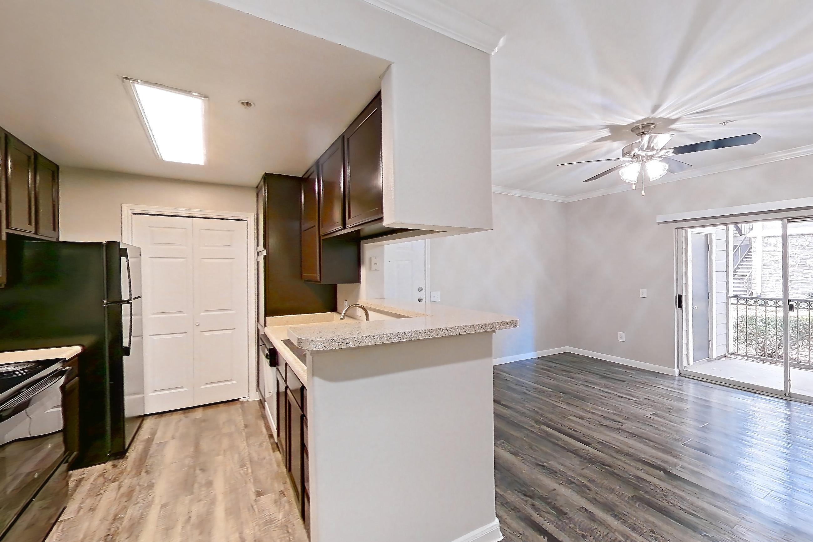 Dining room with black appliances, dark wood-finish flooring, electric range, light countertops, light wood-finish flooring, oven/range, and refrigerator, Apartment 0615 at Marquis on Westheimer