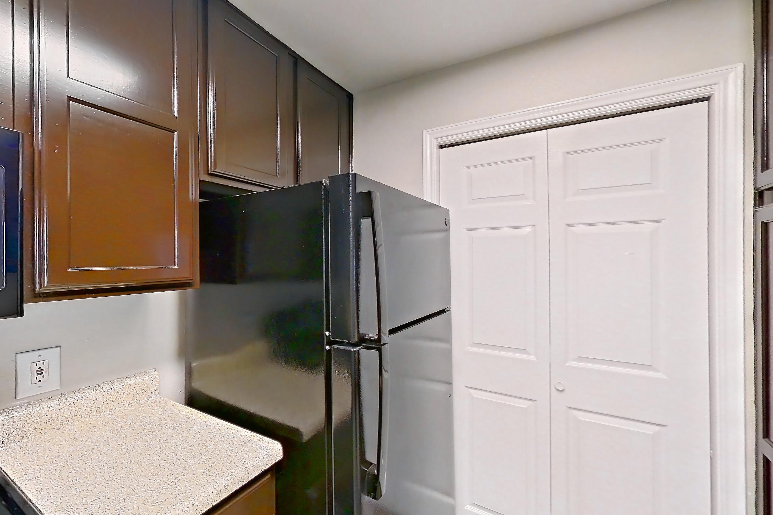 Kitchen with black appliances, dishwasher, electric range, light stone countertops, light wood-finish flooring, oven/range, refrigerator, and white appliances, Apartment 0615 at Marquis on Westheimer