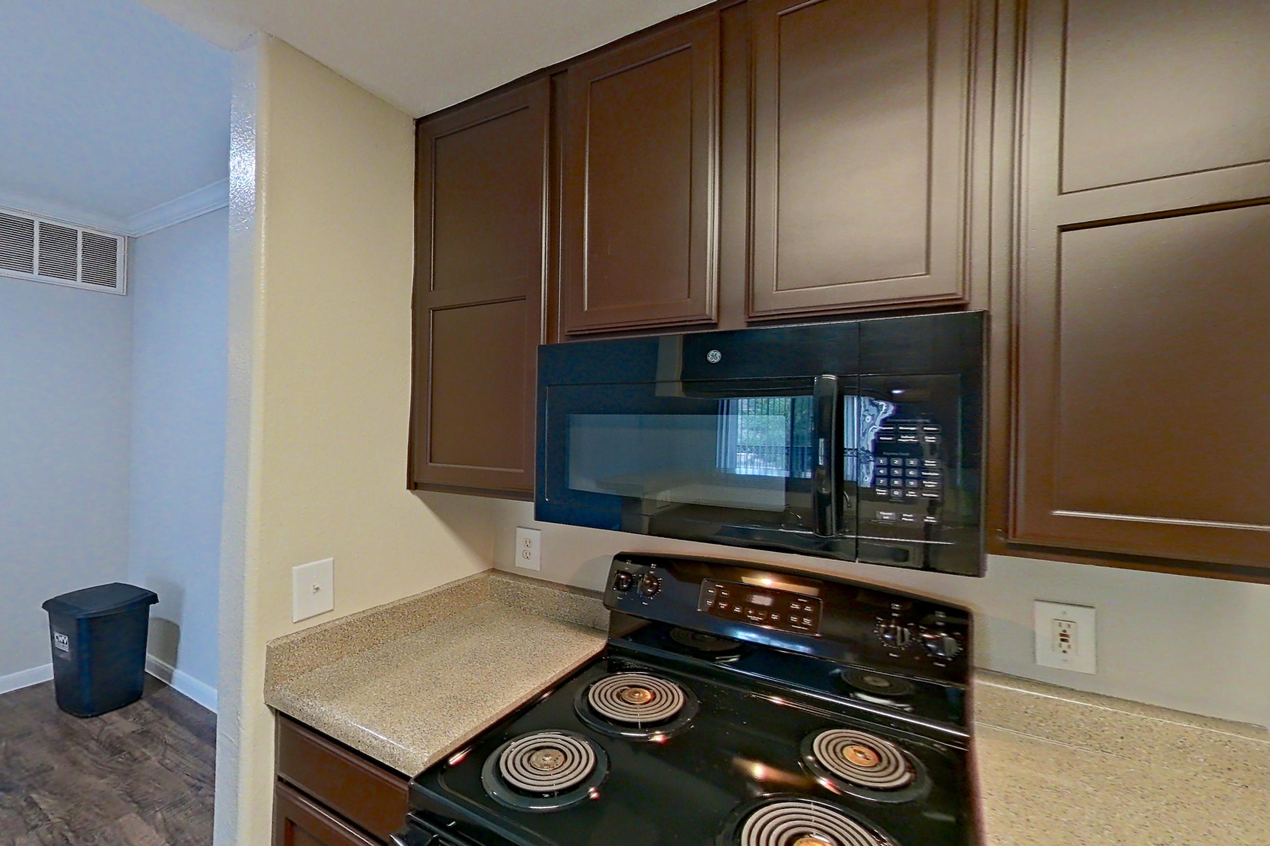 Kitchen with black appliances, dishwasher, electric range, light countertops, microwave, oven/range, refrigerator, and white appliances, Apartment 0631 at Marquis on Westheimer