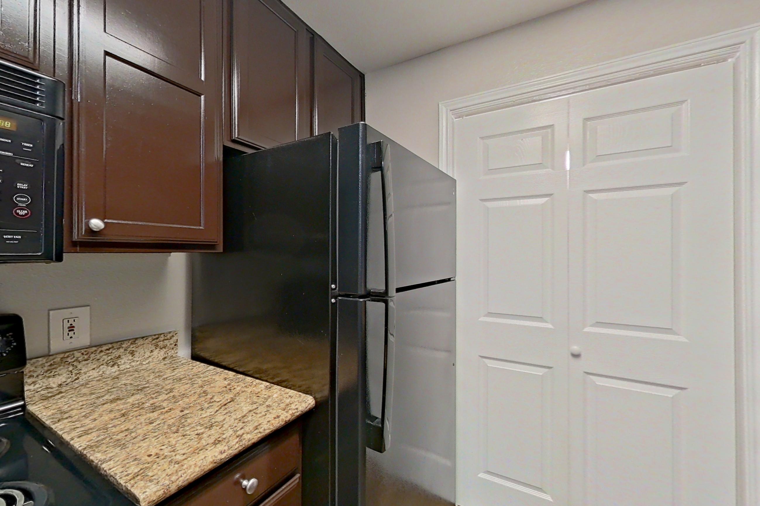 Kitchen with black appliances, dishwasher, light stone countertops, oven/range, and refrigerator, Apartment 0635 at Marquis on Westheimer