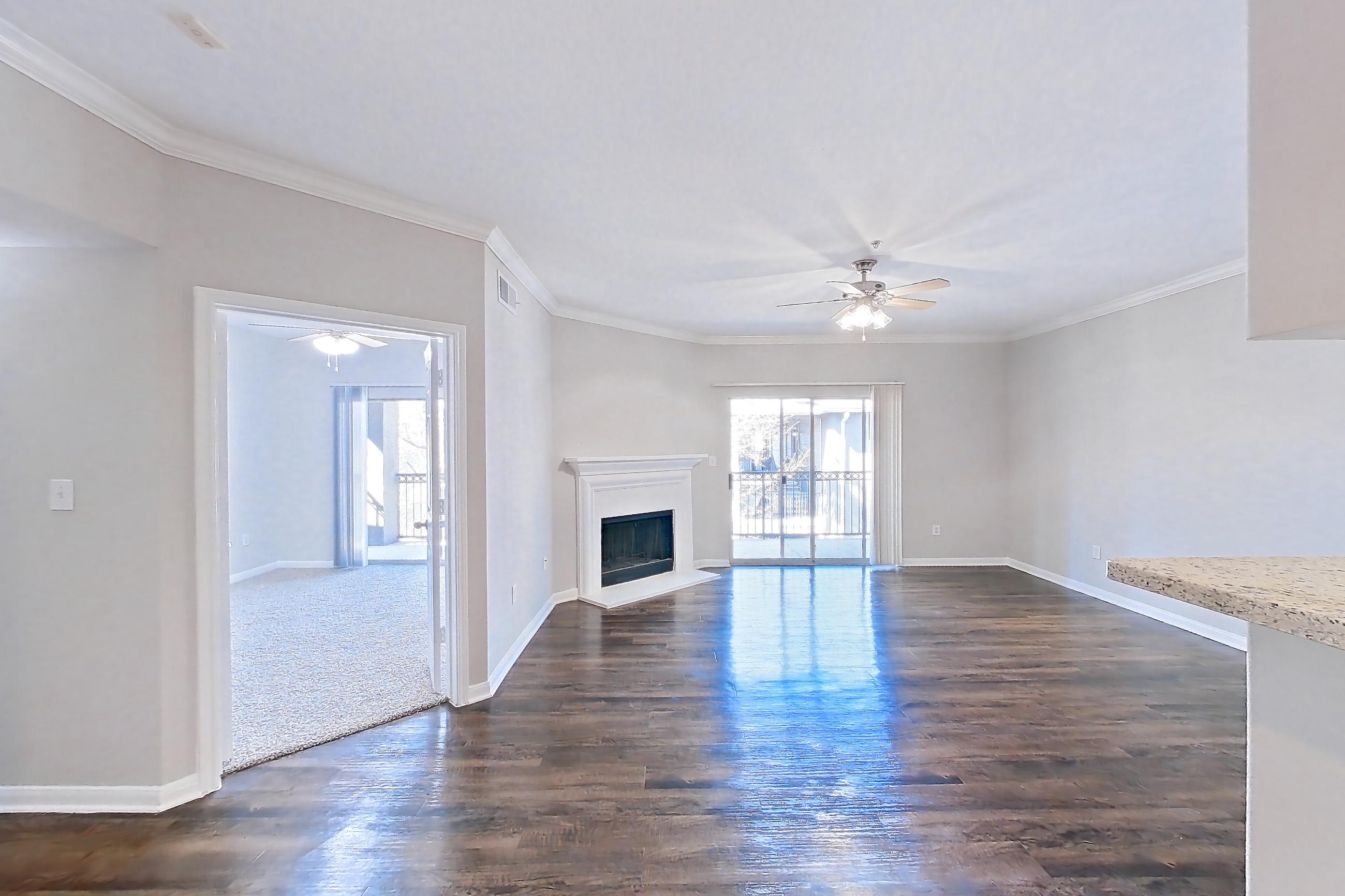 Dining room with black appliances, dark wood-finish flooring, electric range, fireplace, kitchen island, light countertops, light stone countertops, oven/range, refrigerator, and stainless steel appliances, Apartment 0636 at Marquis on Westheimer