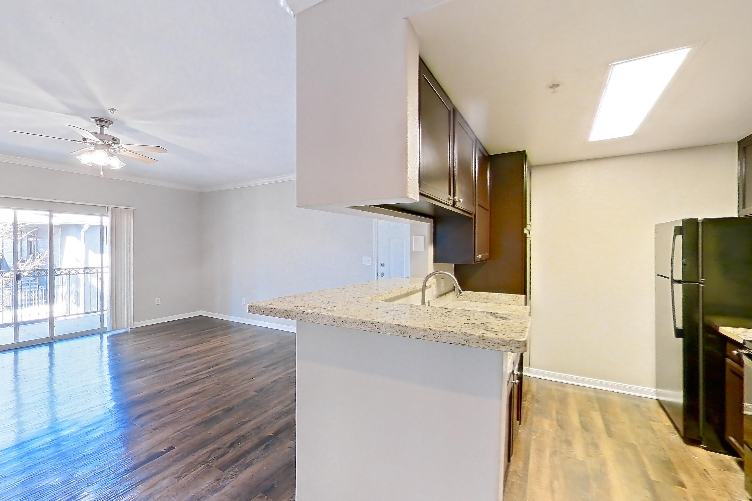 Dining room with black appliances, dark wood-finish flooring, electric range, fireplace, kitchen island, light countertops, light stone countertops, oven/range, refrigerator, and stainless steel appliances, Apartment 0636 at Marquis on Westheimer