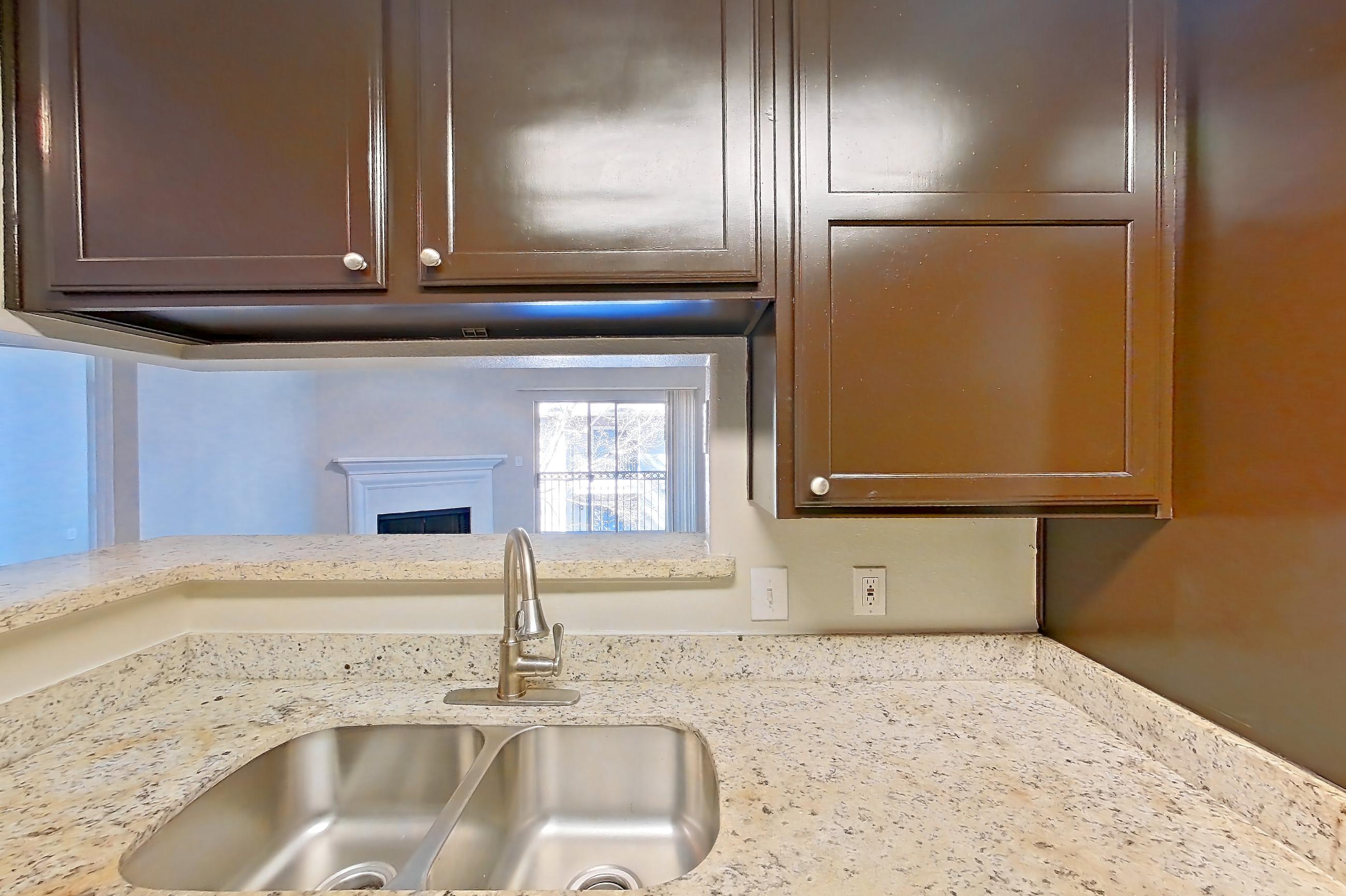 Kitchen with black appliances, dark wood-finish flooring, dishwasher, electric range, light stone countertops, light wood-finish flooring, oven/range, refrigerator, and stainless steel appliances, Apartment 0636 at Marquis on Westheimer
