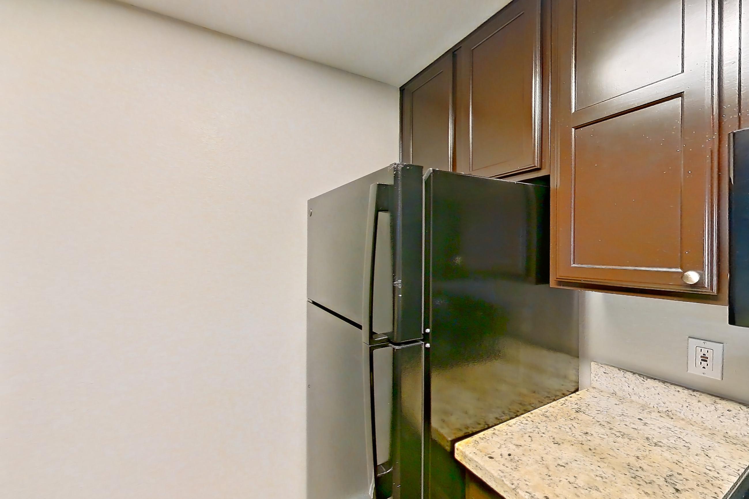 Kitchen with black appliances, dark wood-finish flooring, dishwasher, electric range, light stone countertops, light wood-finish flooring, oven/range, refrigerator, and stainless steel appliances, Apartment 0636 at Marquis on Westheimer