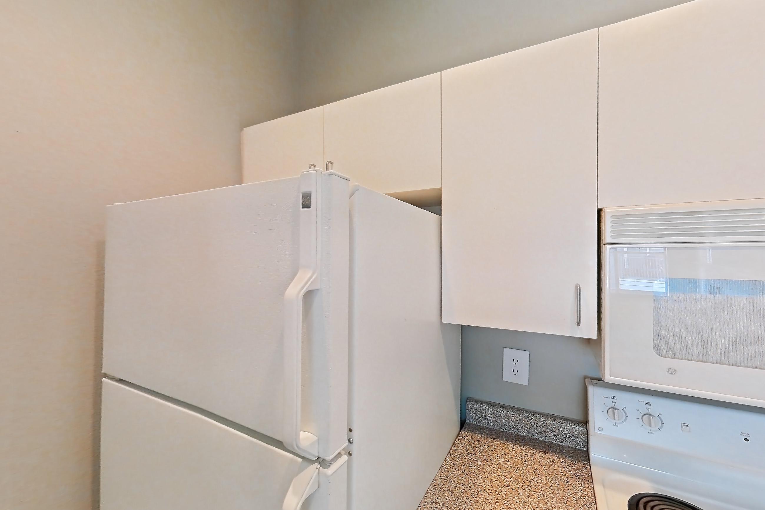 Kitchen with dishwasher, electric range, light countertops, light stone countertops, light wood-finish flooring, microwave, oven/range, refrigerator, and white appliances, Apartment 01-01313 at Marquis on Gaston