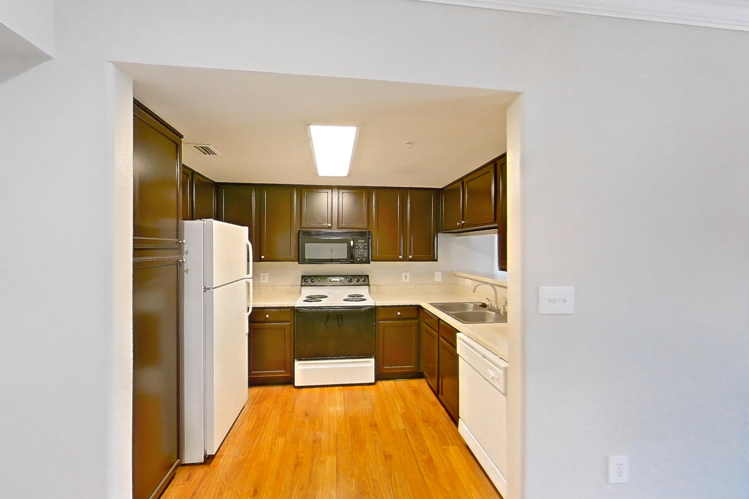 Dining room with dishwasher, electric range, fireplace, light countertops, light wood-finish flooring, oven/range, refrigerator, white appliances, and wood-finish flooring, Apartment 0732 at Marquis on Westheimer