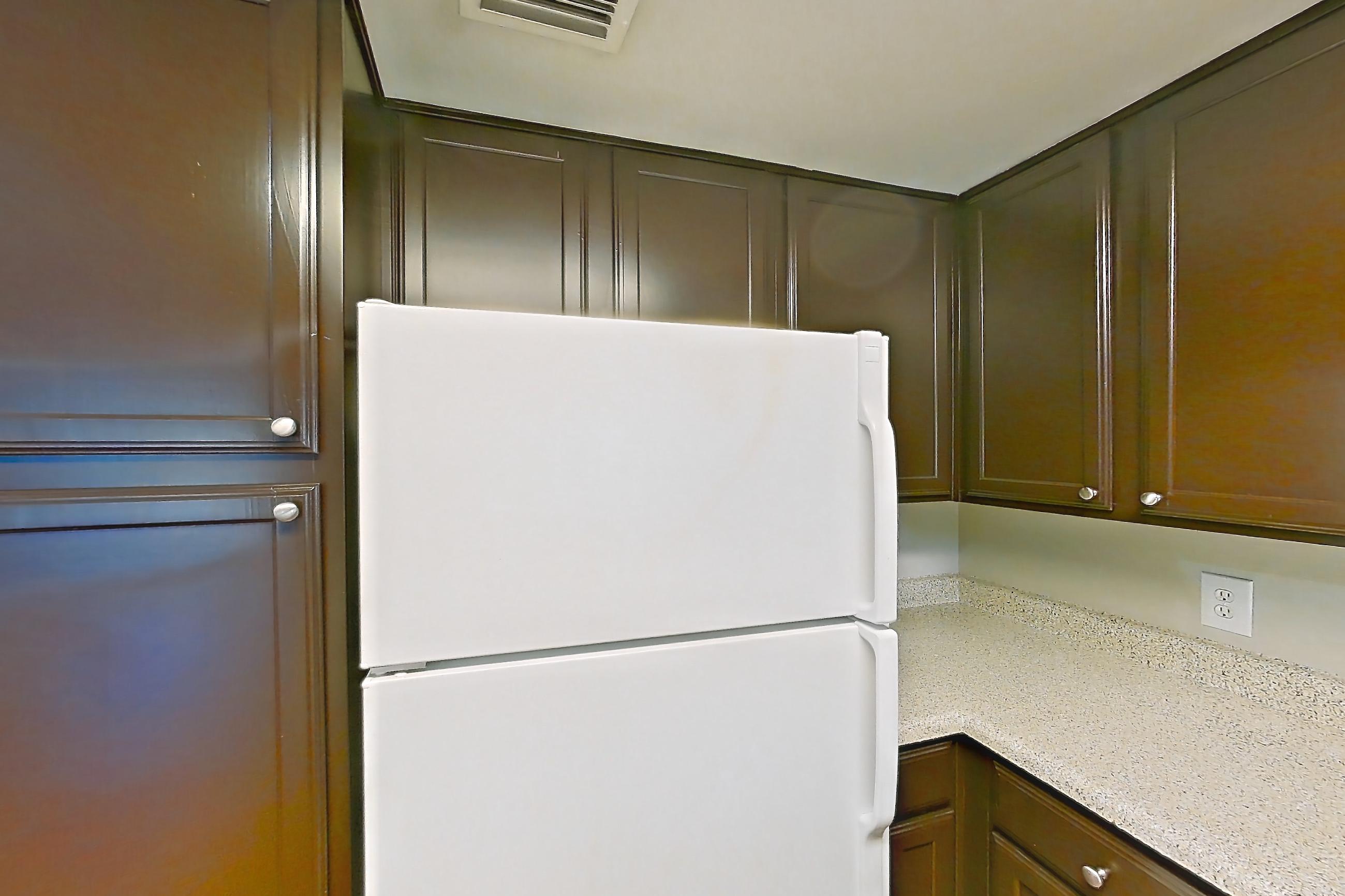 Kitchen with black appliances, electric range, light countertops, light stone countertops, light wood-finish flooring, microwave, oven/range, refrigerator, white appliances, and wood-finish flooring, Apartment 0732 at Marquis on Westheimer