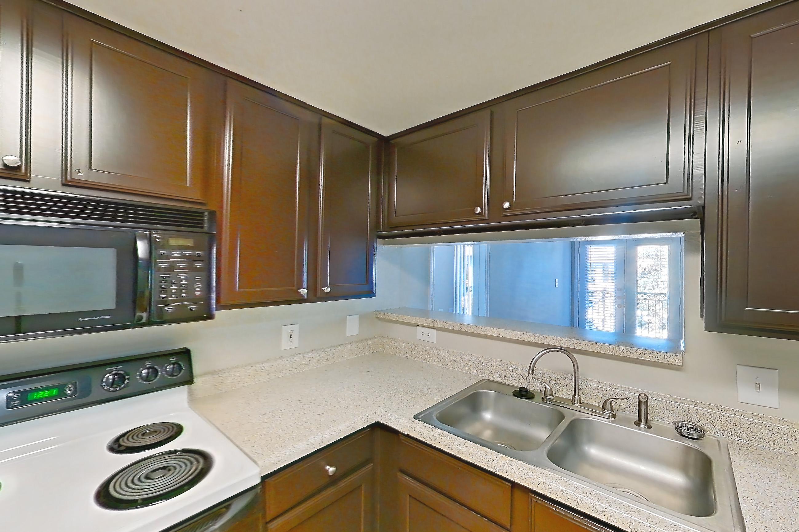 Kitchen with black appliances, electric range, light countertops, light stone countertops, light wood-finish flooring, microwave, oven/range, refrigerator, white appliances, and wood-finish flooring, Apartment 0732 at Marquis on Westheimer