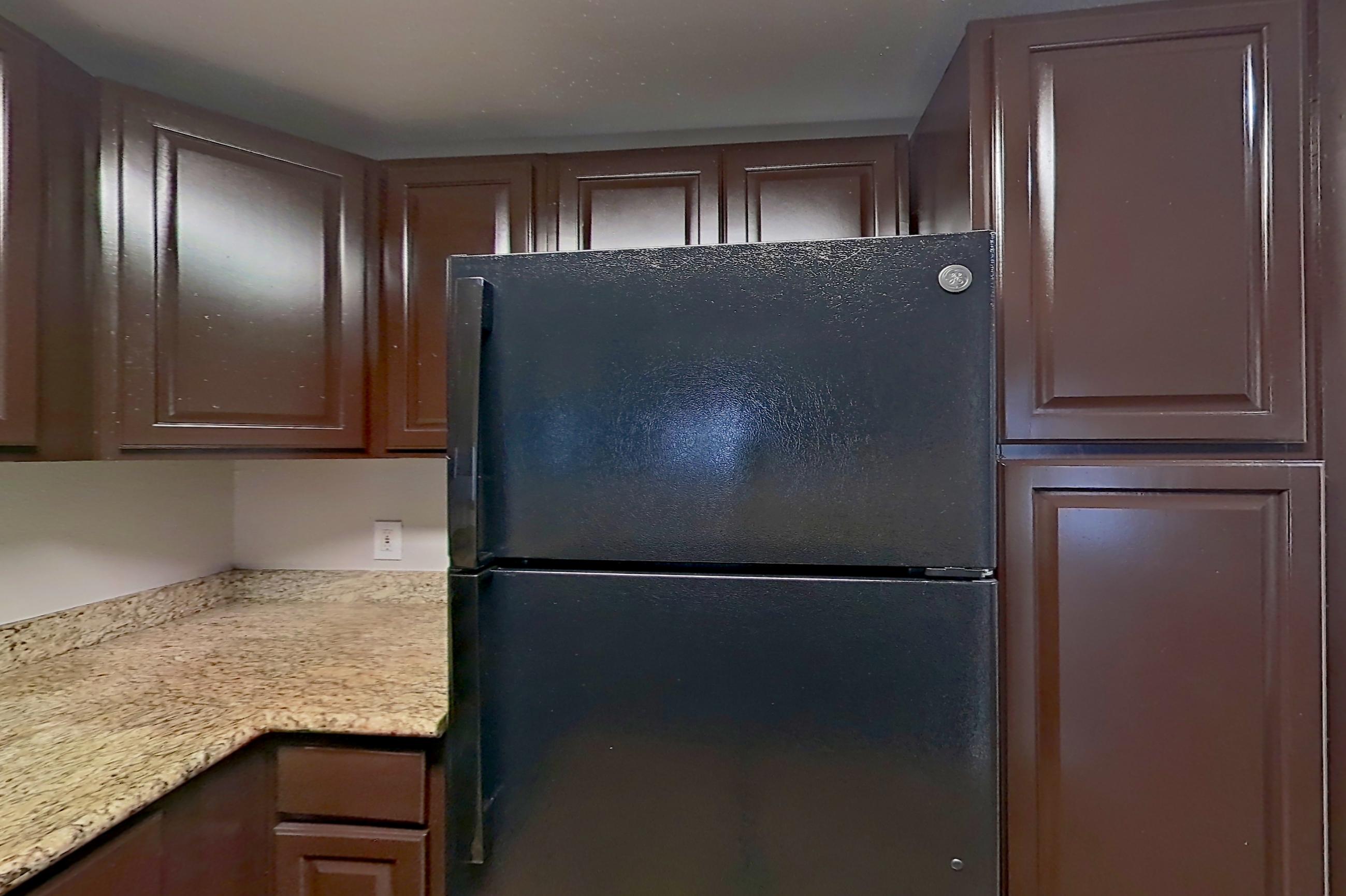 Kitchen with black appliances, dishwasher, electric range, light countertops, light stone countertops, light wood-finish flooring, microwave, oven/range, and refrigerator, Apartment 0821 at Marquis on Westheimer
