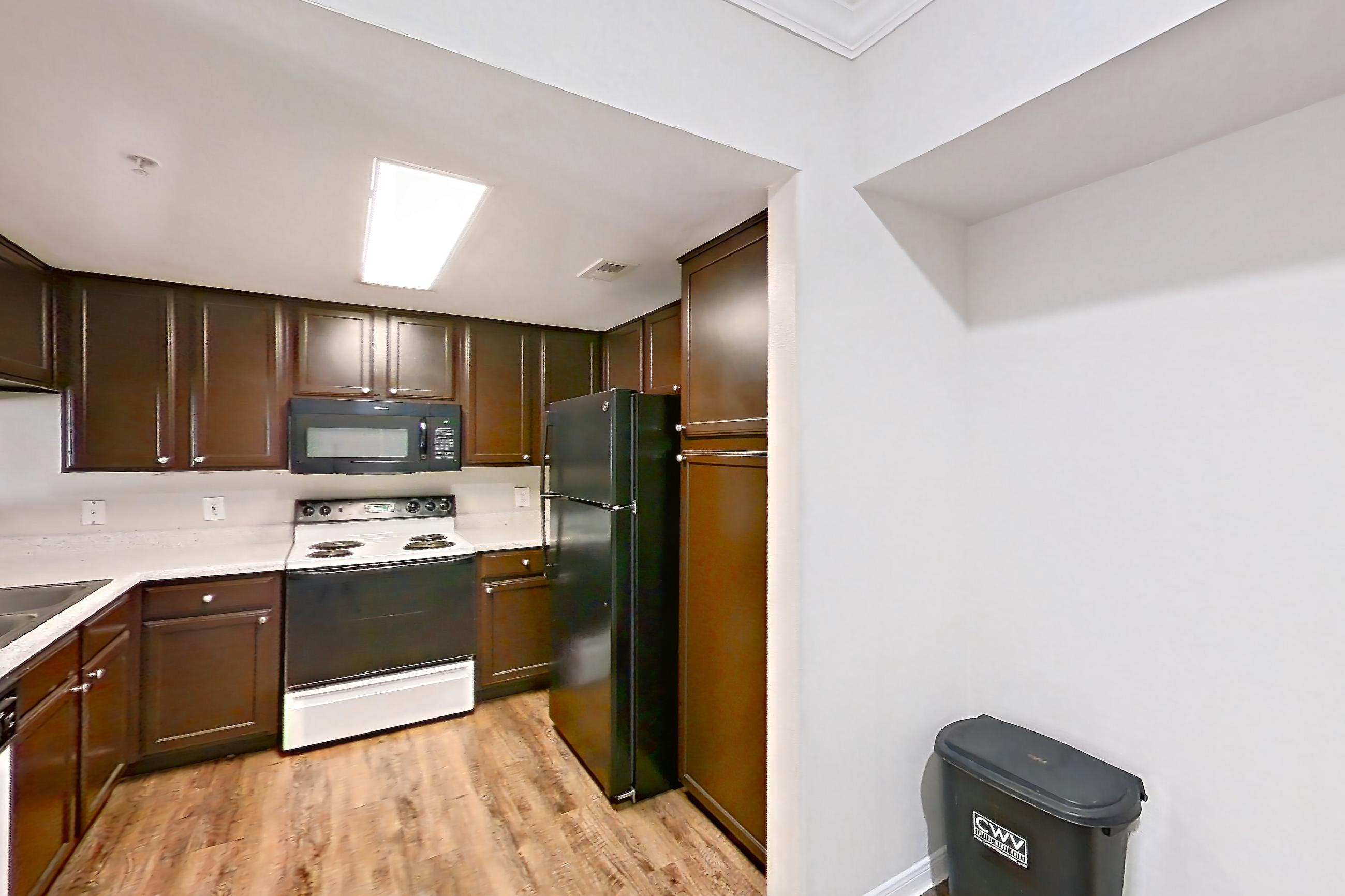 Dining room with black appliances, dark wood-finish flooring, dishwasher, electric range, fireplace, light countertops, light wood-finish flooring, oven/range, range hood, refrigerator, and white appliances, Apartment 0923 at Marquis on Westheimer