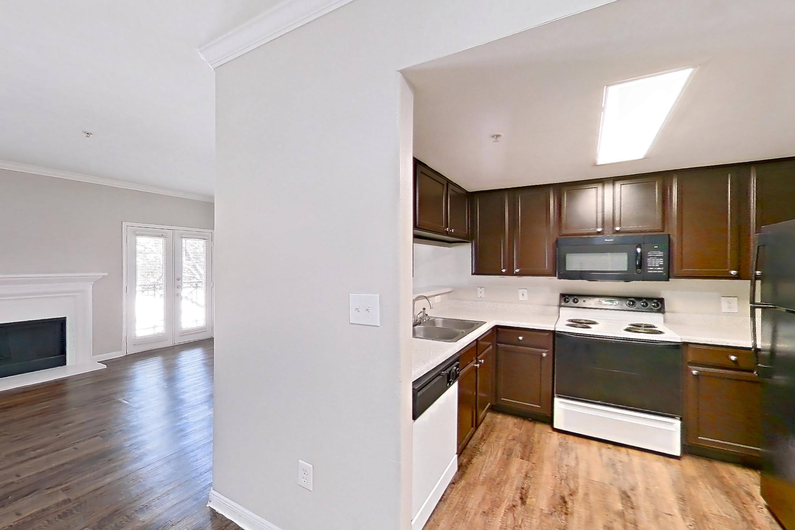 Dining room with black appliances, dark wood-finish flooring, dishwasher, electric range, fireplace, light countertops, light wood-finish flooring, oven/range, range hood, refrigerator, and white appliances, Apartment 0923 at Marquis on Westheimer