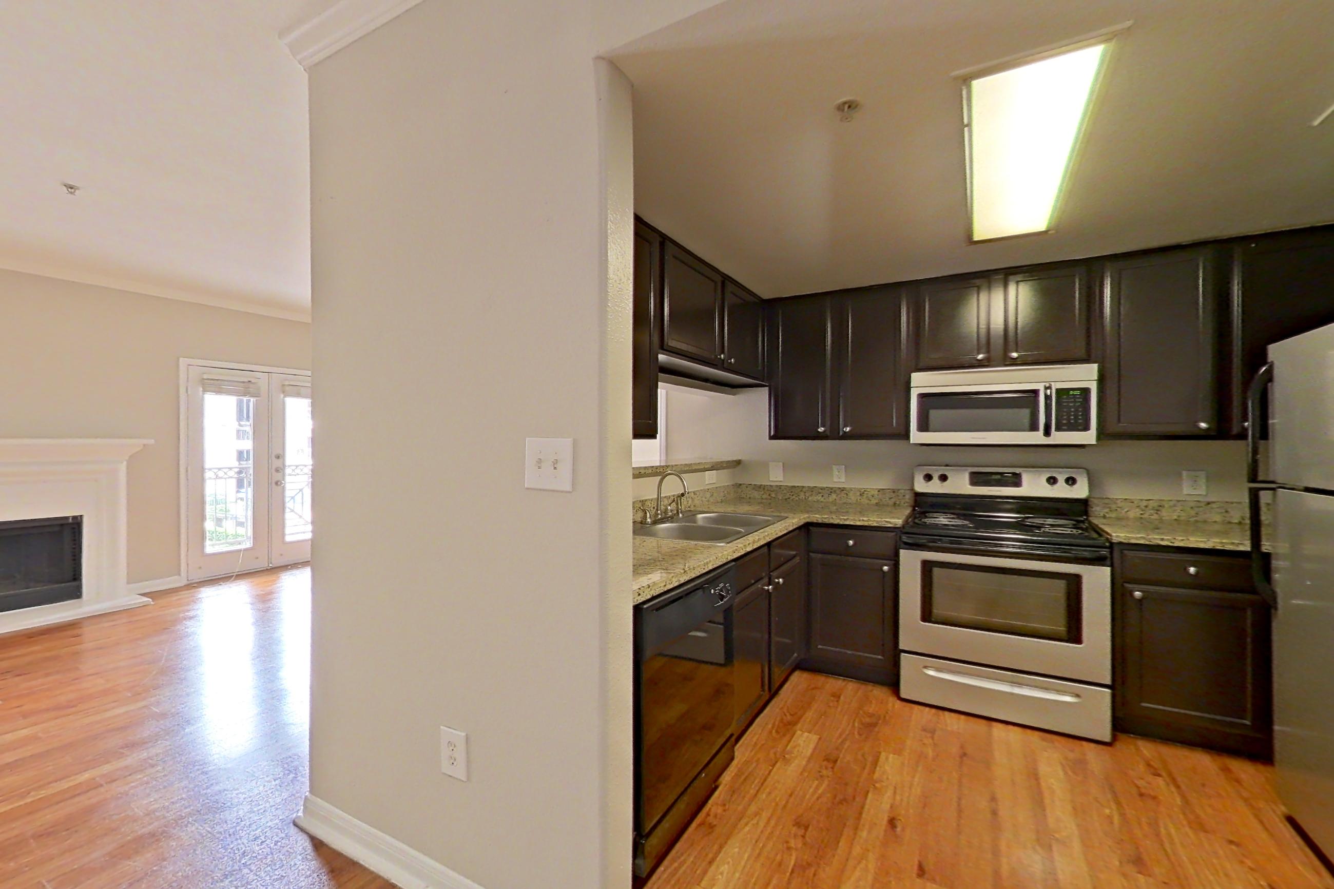 Dining room with electric range, fireplace, light stone countertops, light wood-finish flooring, microwave, oven/range, refrigerator, stainless steel appliances, and wood-finish flooring, Apartment 0927 at Marquis on Westheimer